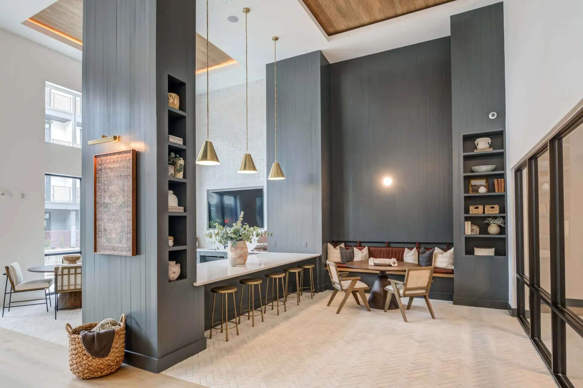 Modern communal lounge area with a long counter, bar stools, and a built-in banquette seating area at The Grayson apartments in Fort Worth, TX..