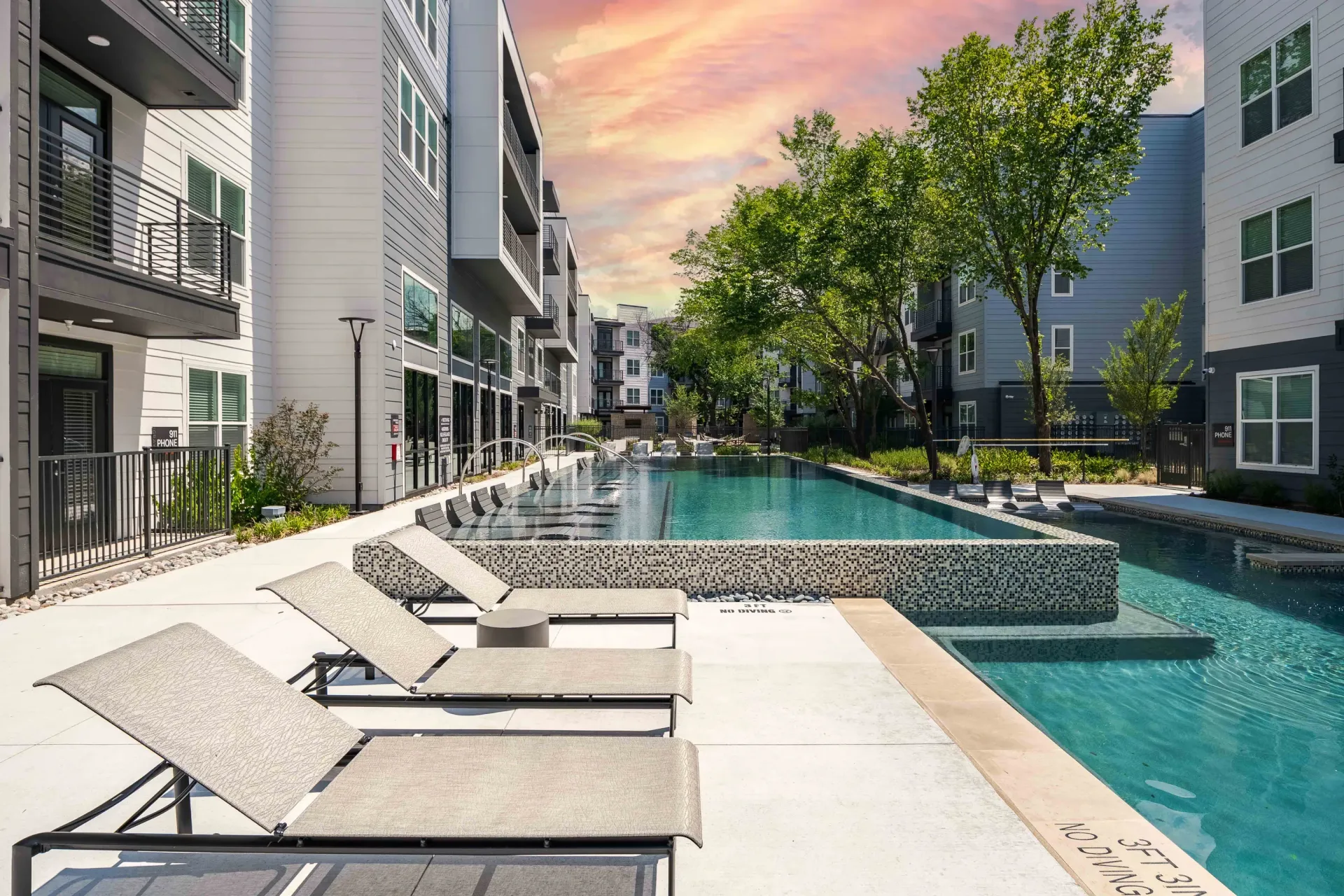 Swimming pool with lounge chairs and apartment buildings at The Grayson in Fort Worth, TX.