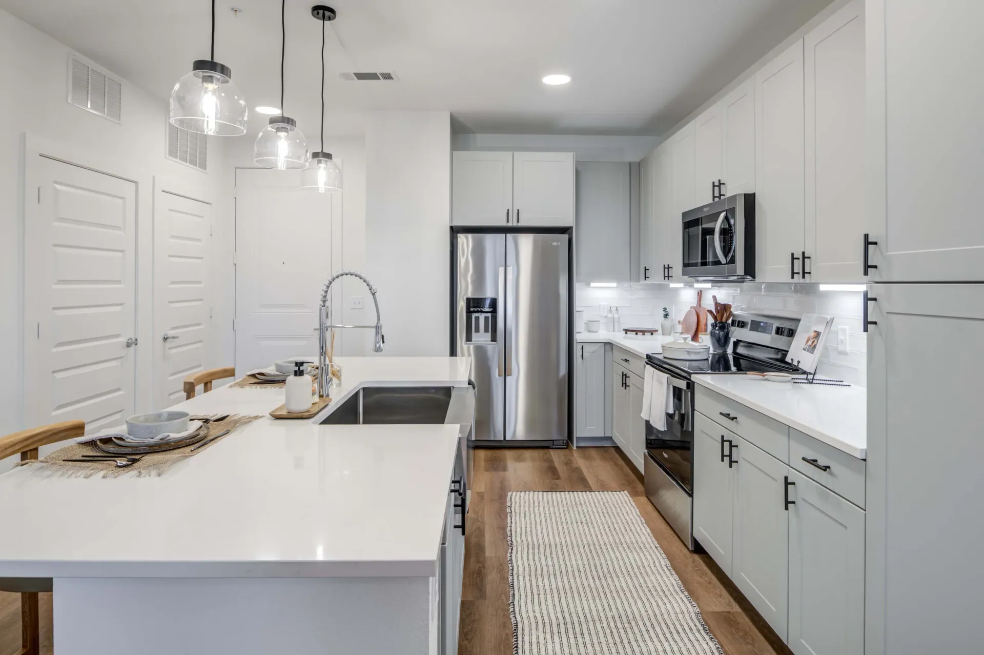 Modern kitchen with white countertops, stainless steel appliances, and light gray cabinets at The Grayson.