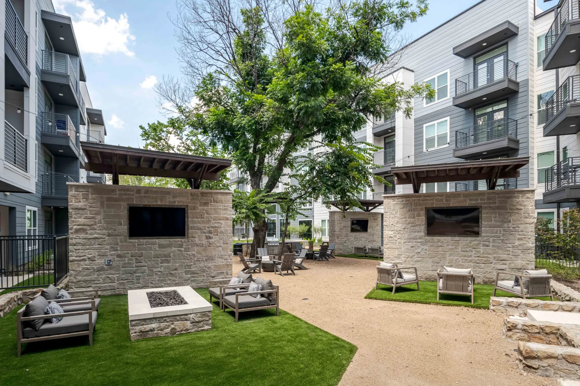 Outdoor lounge area with modern seating, fire pit, and large TVs at The Grayson in Fort Worth, TX.