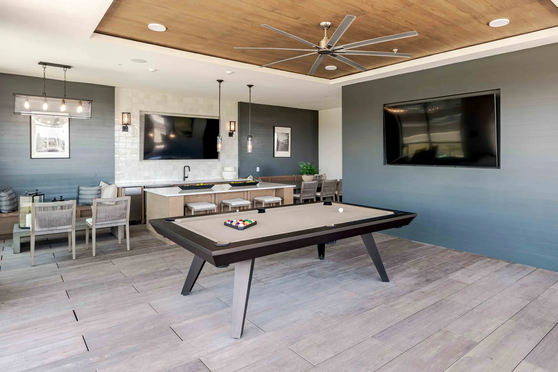 Billiard table in the community lounge with bar seating and TVs at The Grayson in Fort Worth, TX.