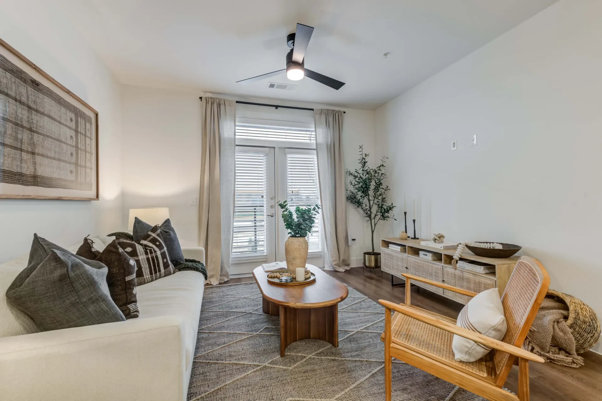 Living room with a white couch, coffee table, accent chair, and a ceiling fan at The Grayson.