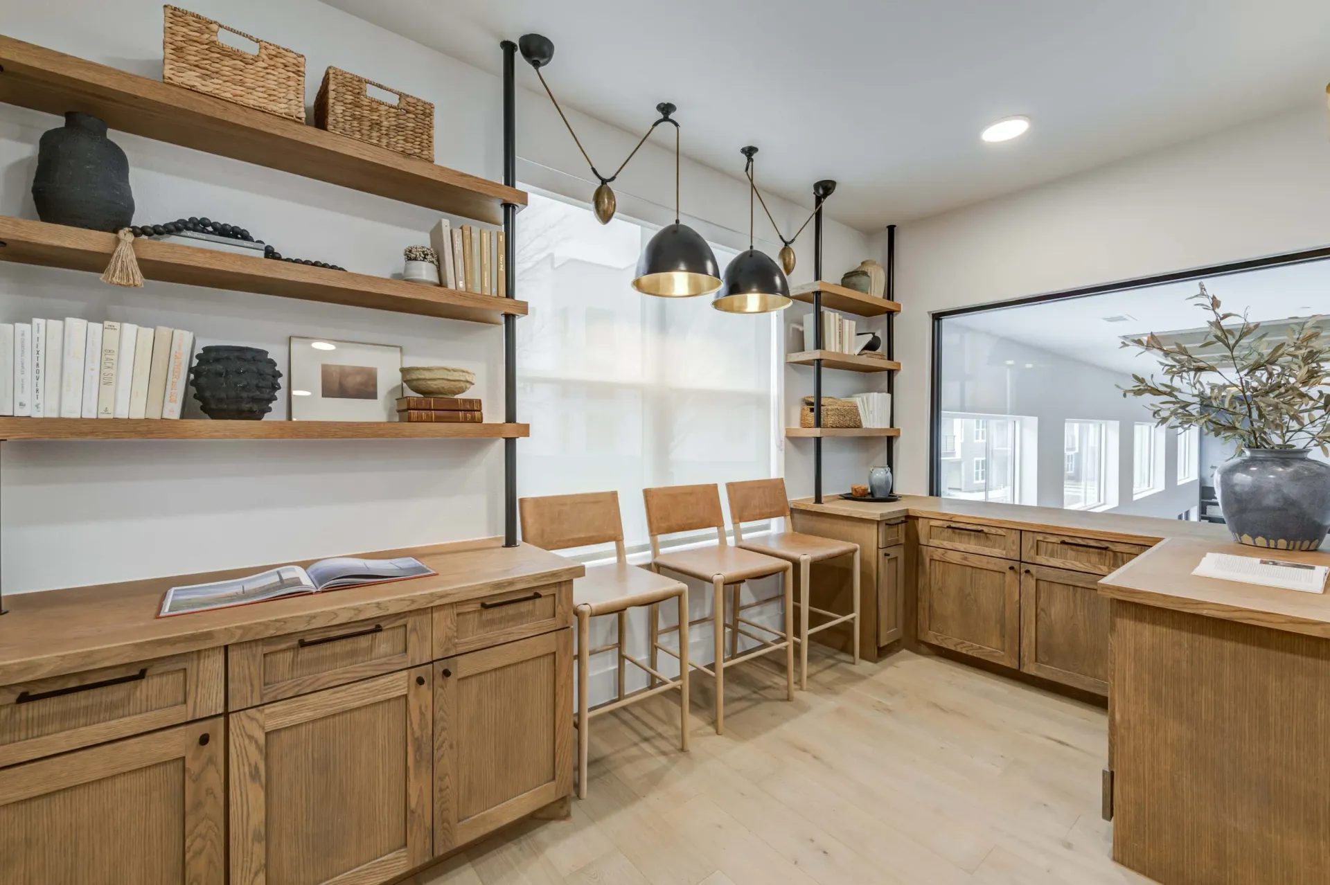 Stylish workspace with built-in wooden cabinets, shelves, and three counter stools at The Grayson apartments in Fort Worth, TX..
