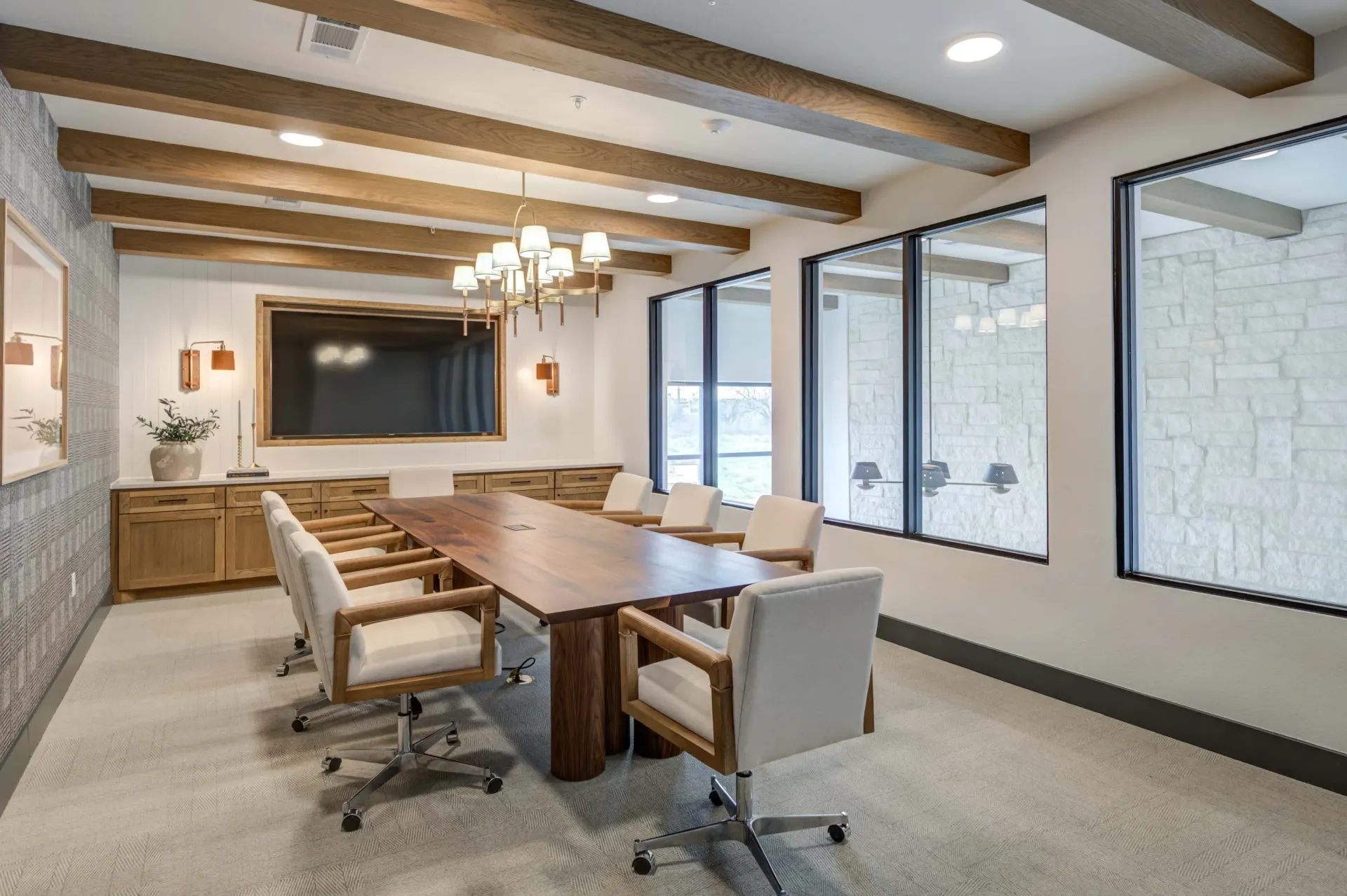 Conference room with a large wooden table and chairs, a TV screen, and large windows at The Grayson apartments in Fort Worth, TX..