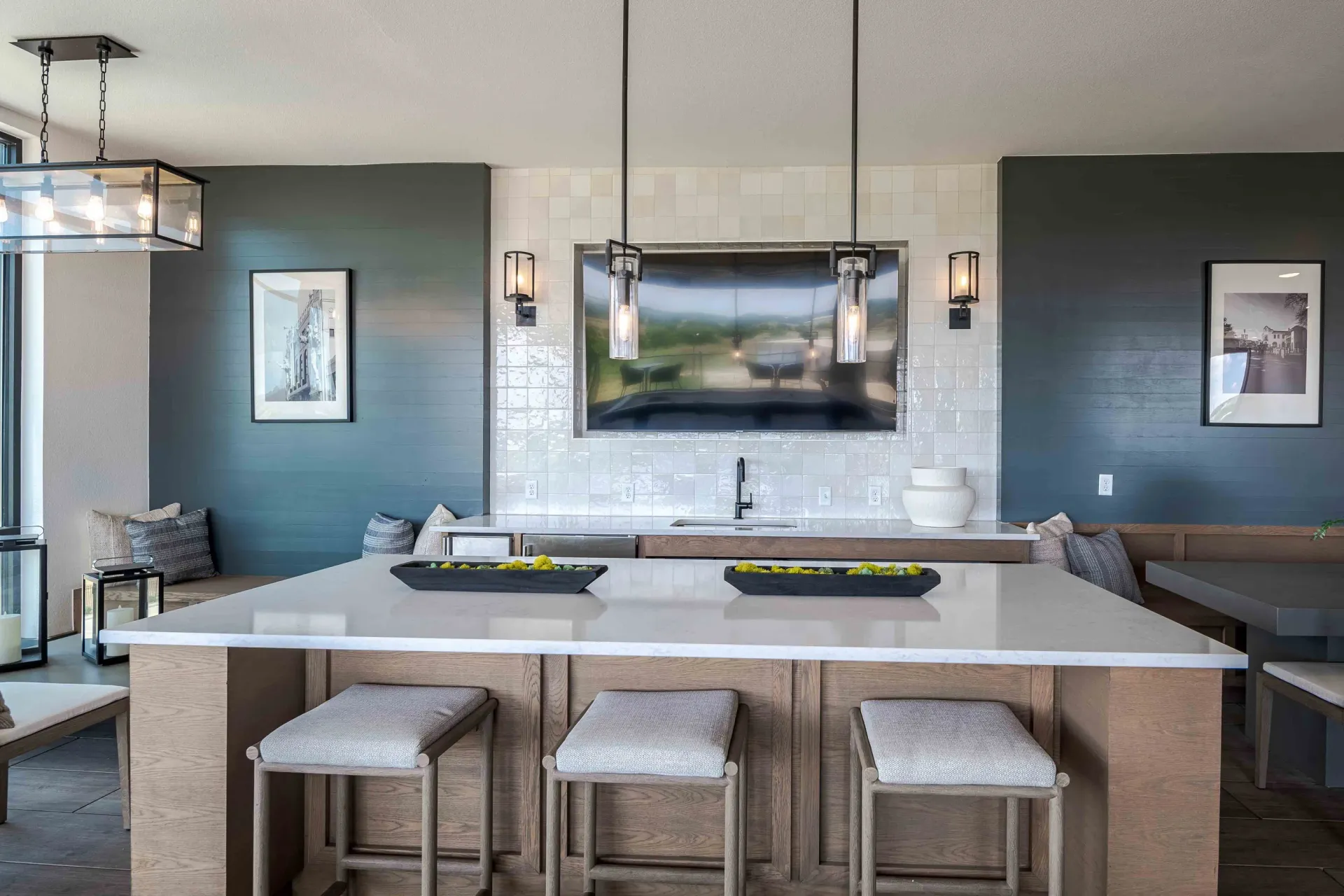 Modern kitchen island with bar stools and a sleek television mounted above the sink area at The Grayson in Fort Worth, TX.