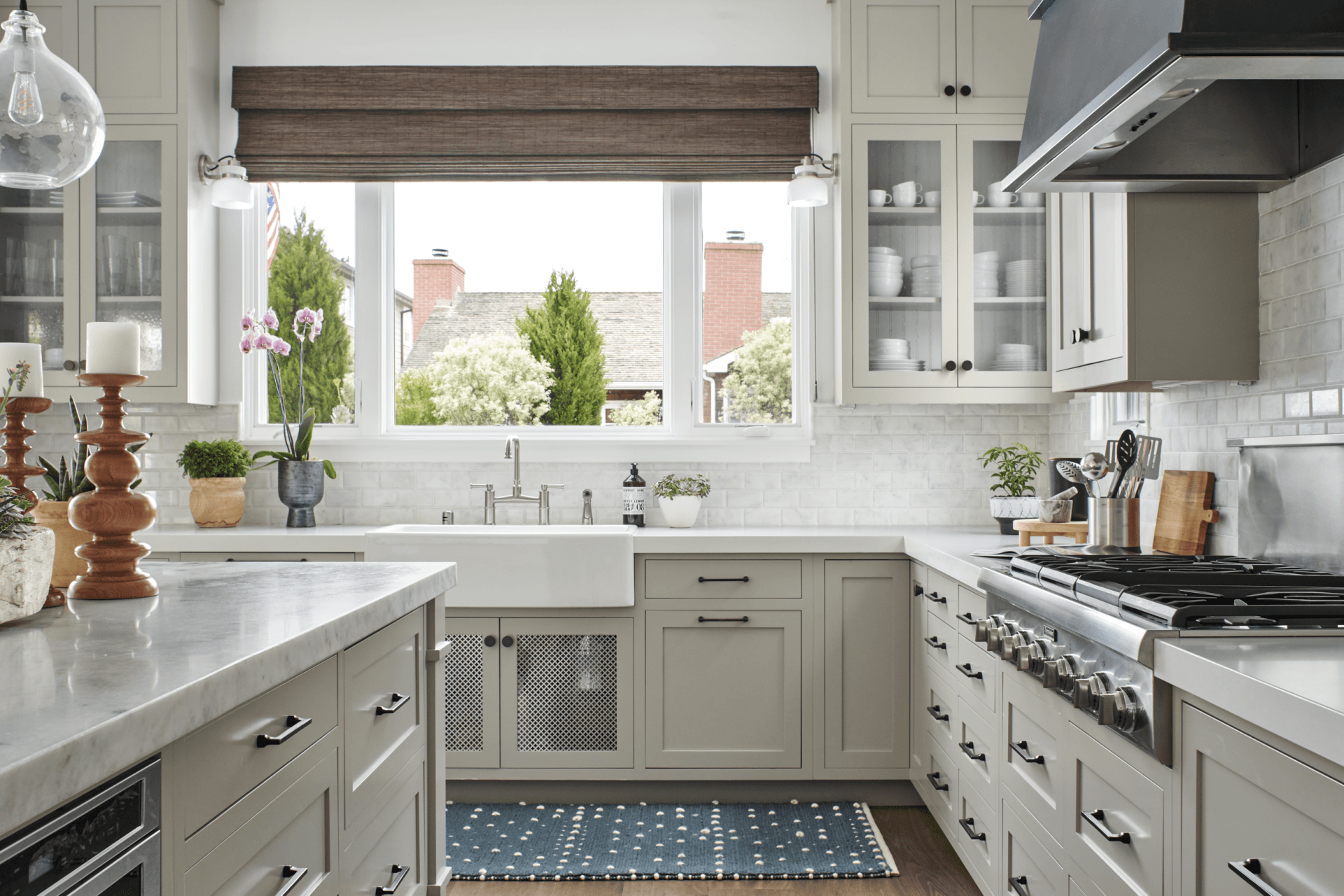 A kitchen with white cabinets , a stove , a sink , and a window.
