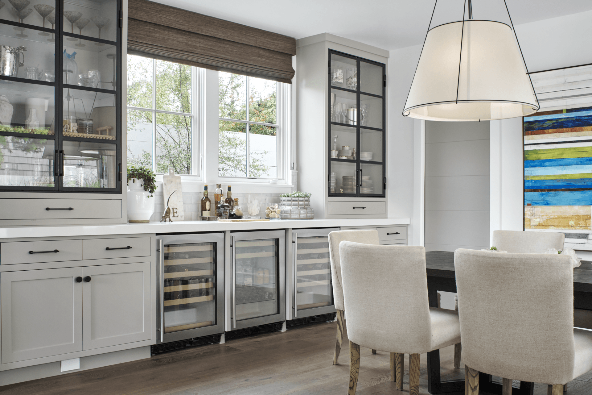 A kitchen with white cabinets , stainless steel appliances , a table and chairs.