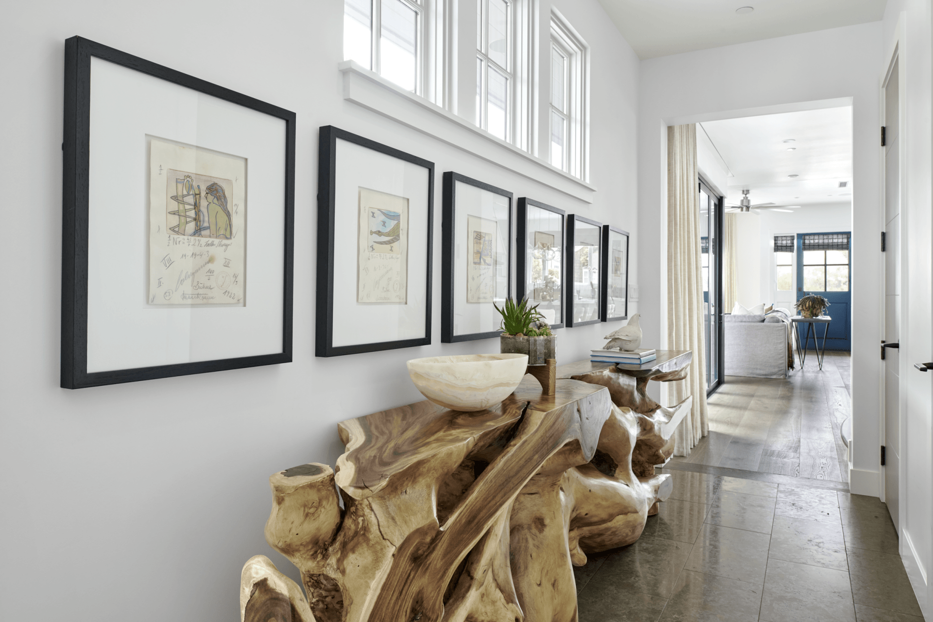 A hallway with a wooden table and a row of framed pictures on the wall.