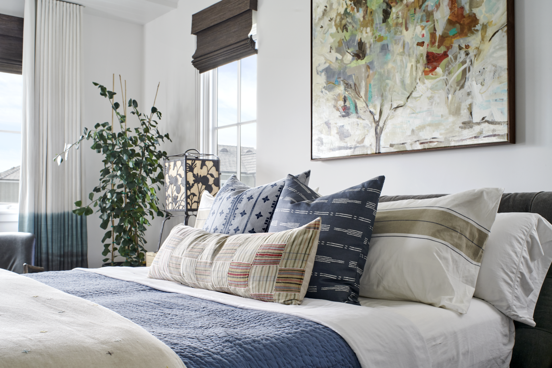 A bedroom with a bed , pillows and a painting on the wall.