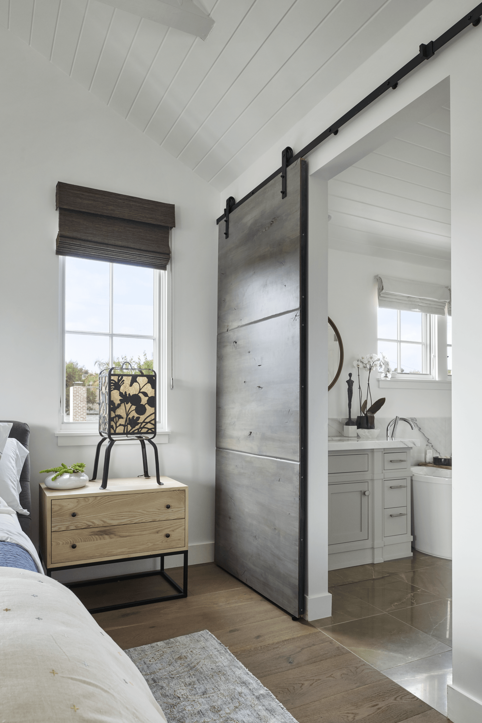 A bedroom with a sliding barn door leading to a bathroom.