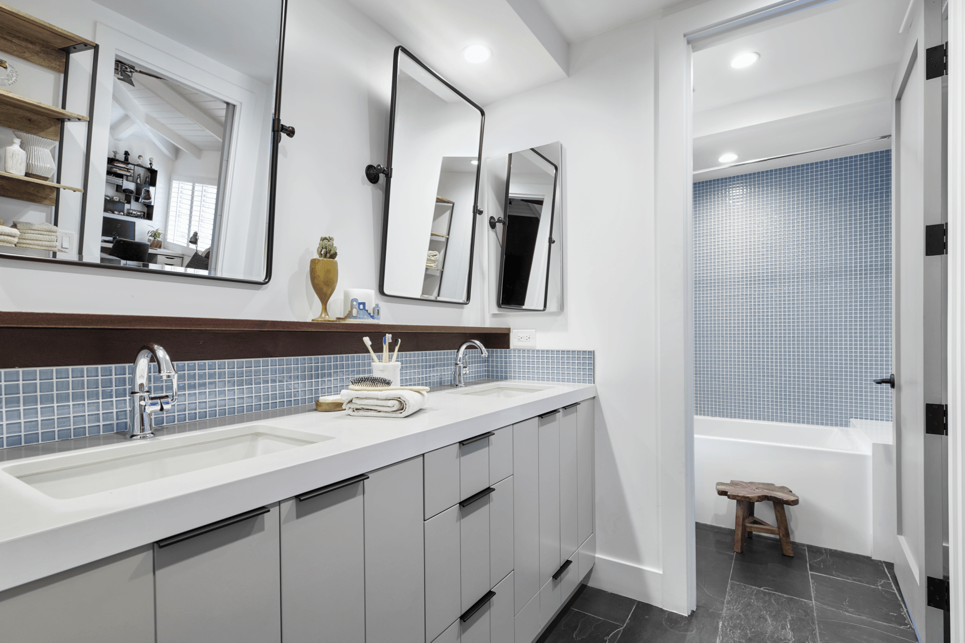A bathroom with two sinks , two mirrors and a bathtub.