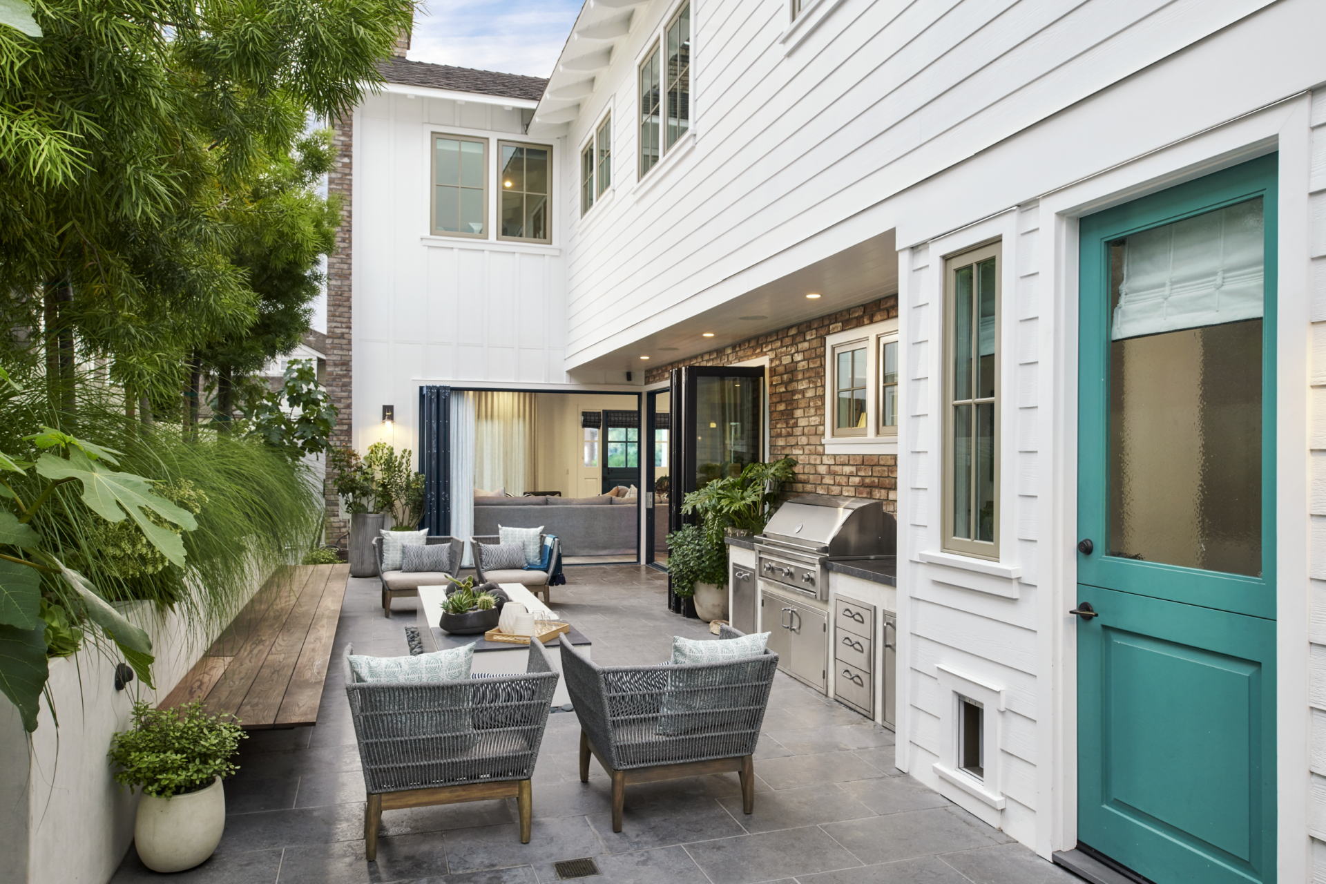 A white house with a blue door and a patio with chairs and a table.