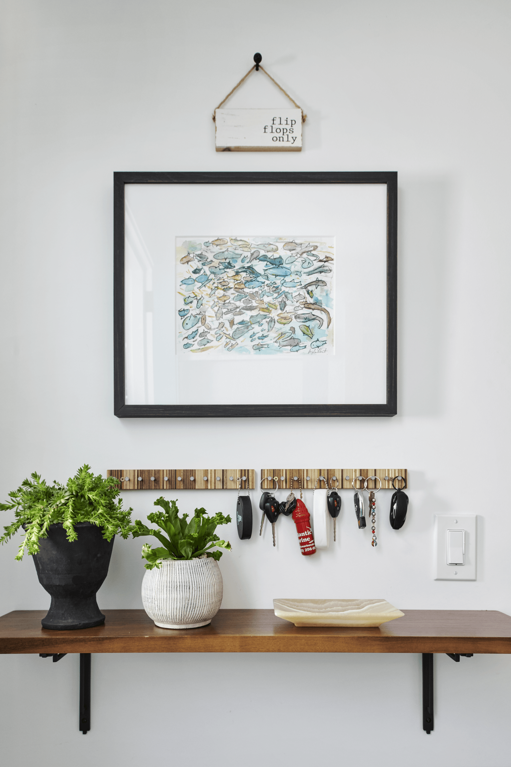 A framed picture hangs above a shelf with keys hanging from it