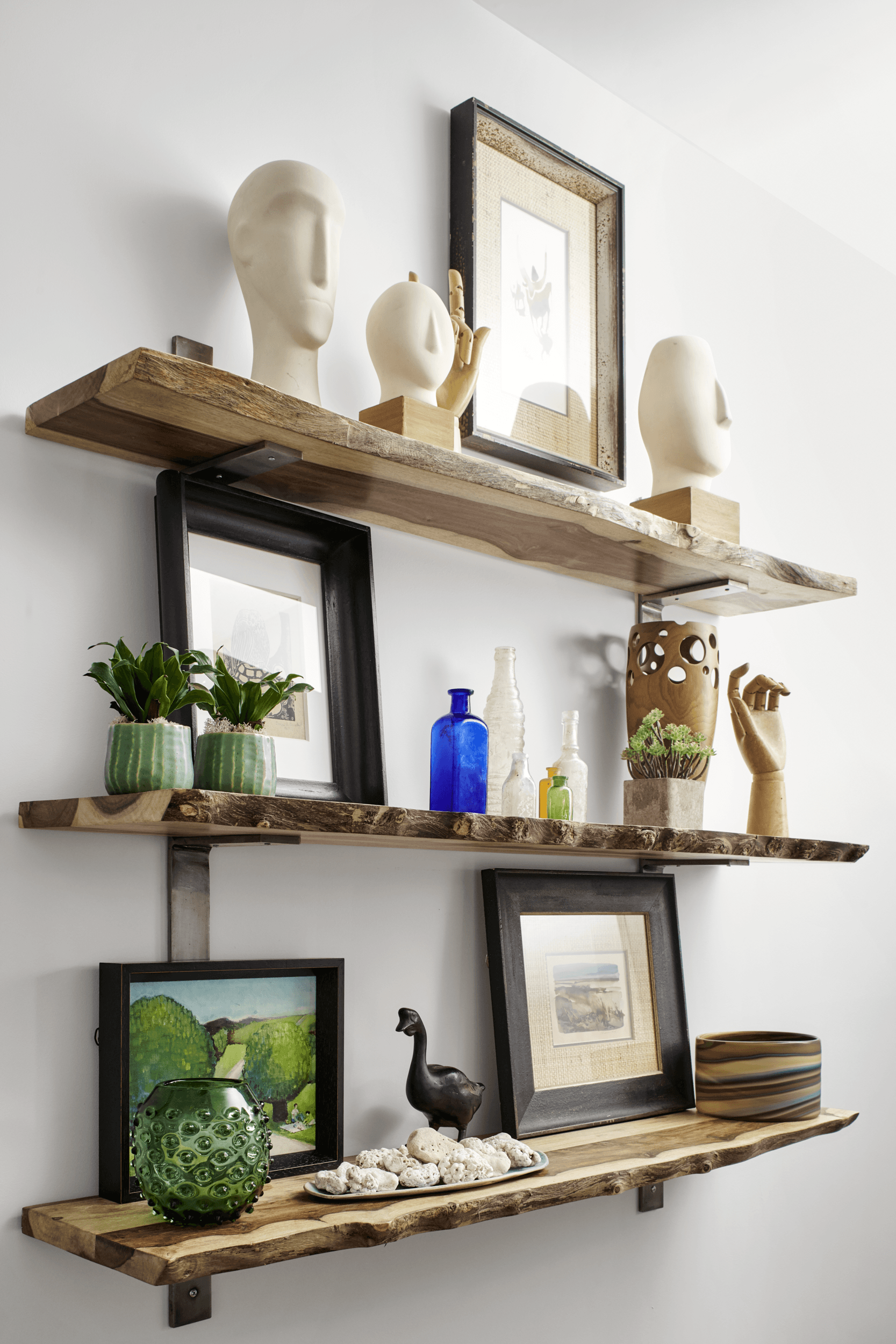 A wooden shelf filled with pictures , vases , and plants.