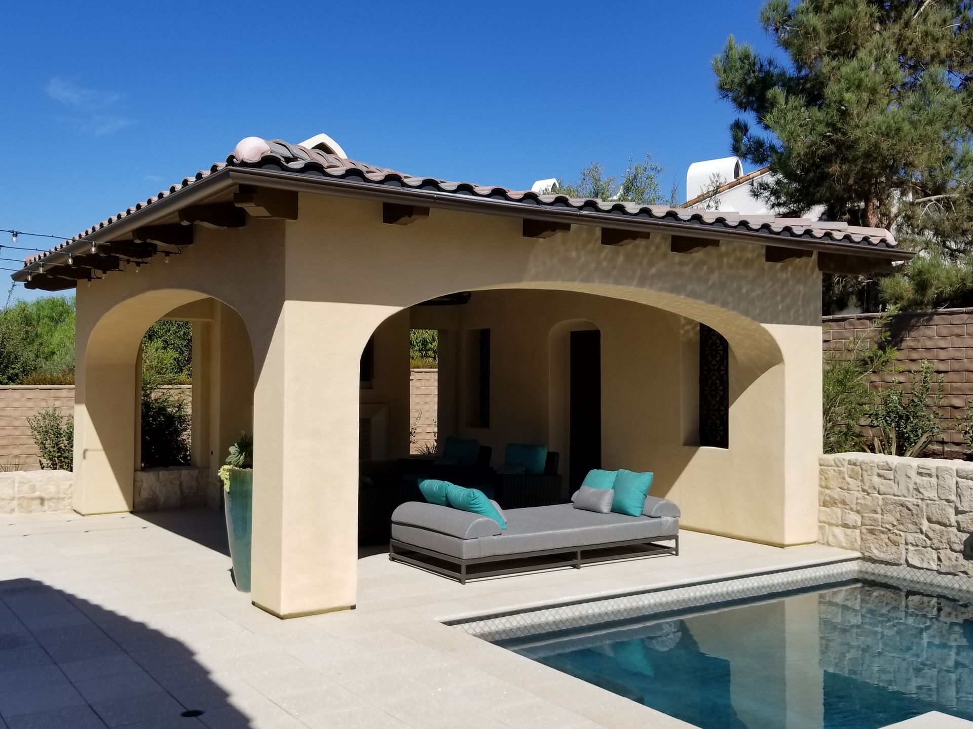 A patio with a couch and a pool in front of it