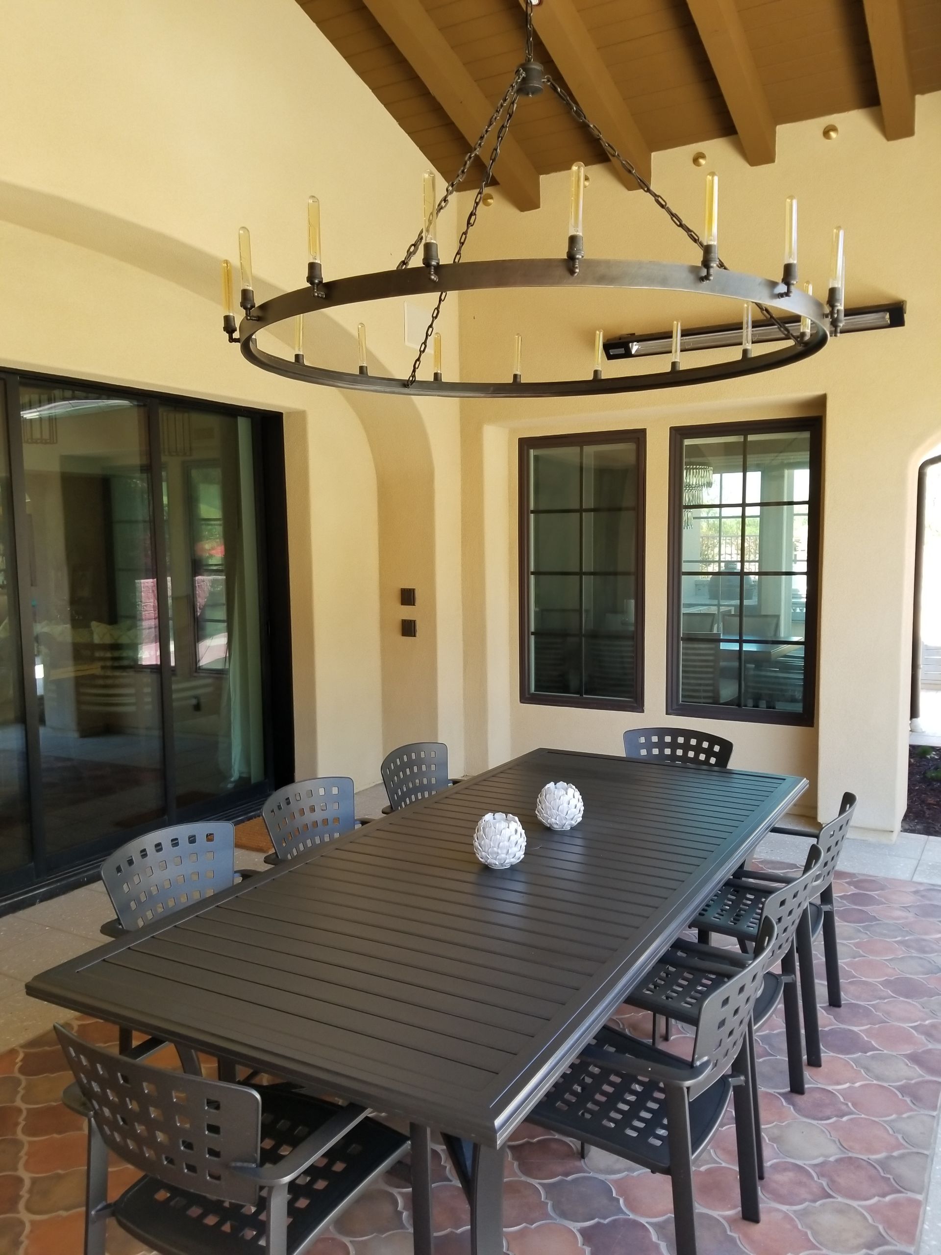 A patio with a table and chairs and a chandelier hanging from the ceiling
