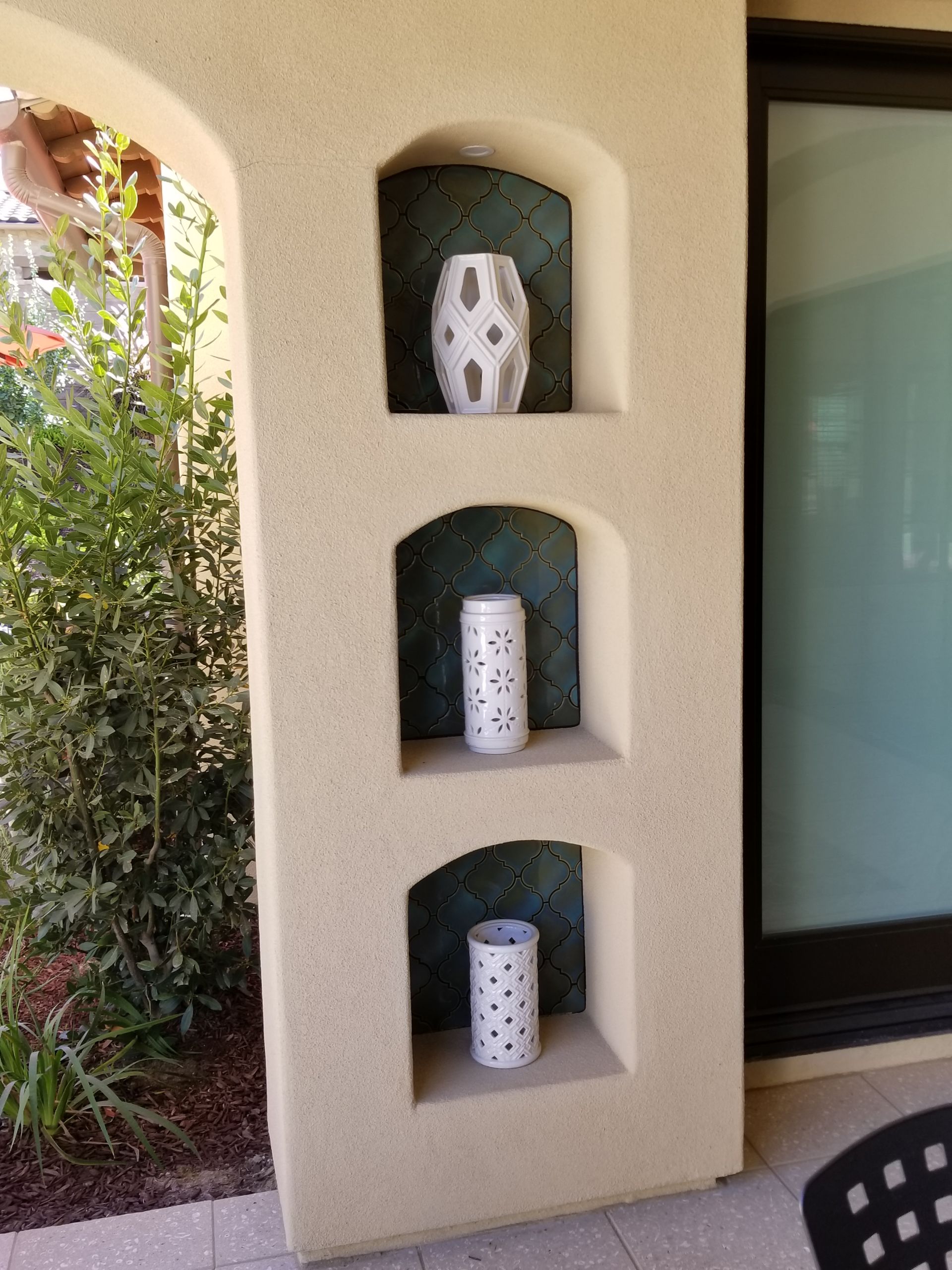 Three vases are displayed on a wall next to a sliding glass door
