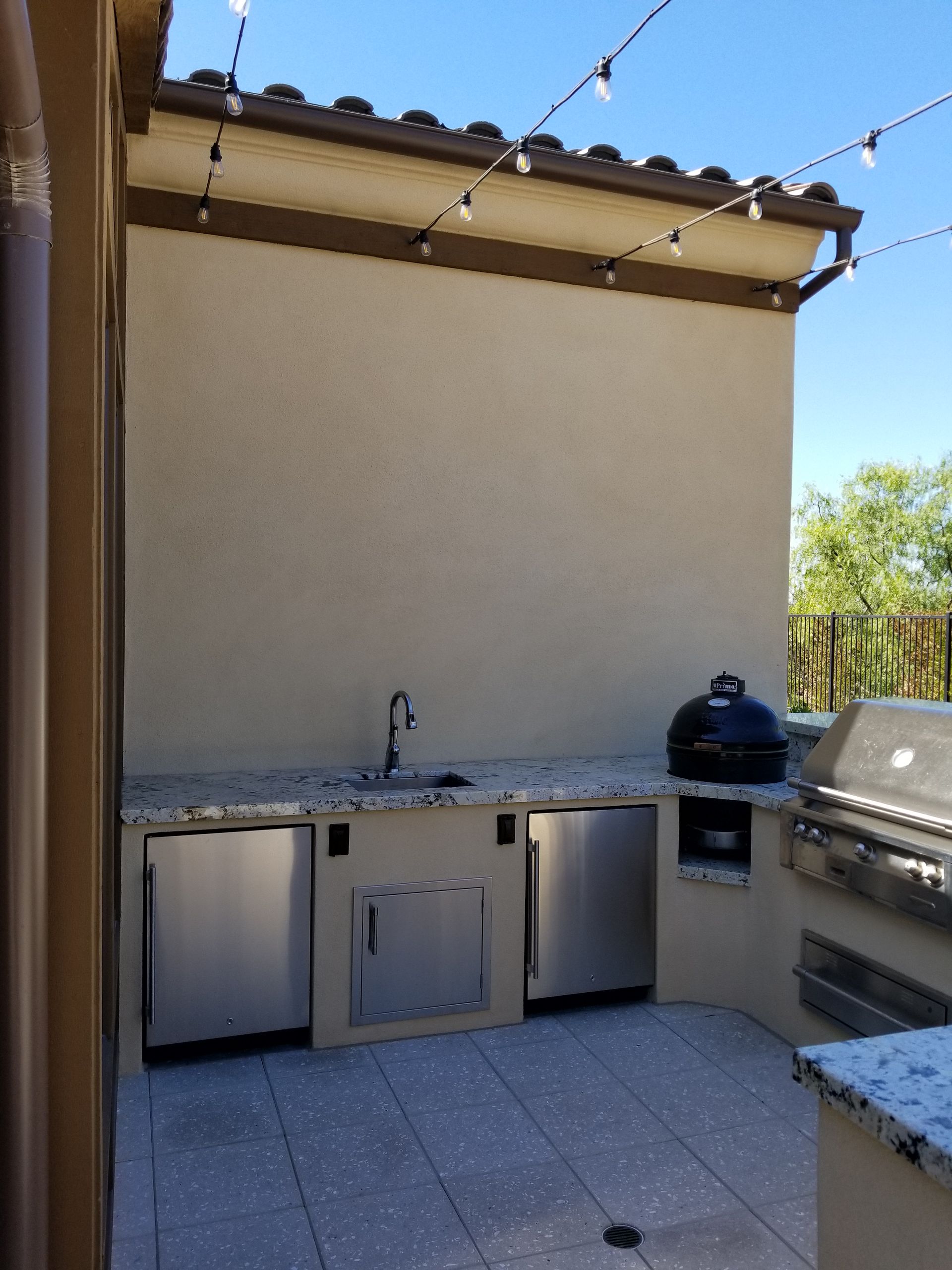 An outdoor kitchen with a sink and a grill