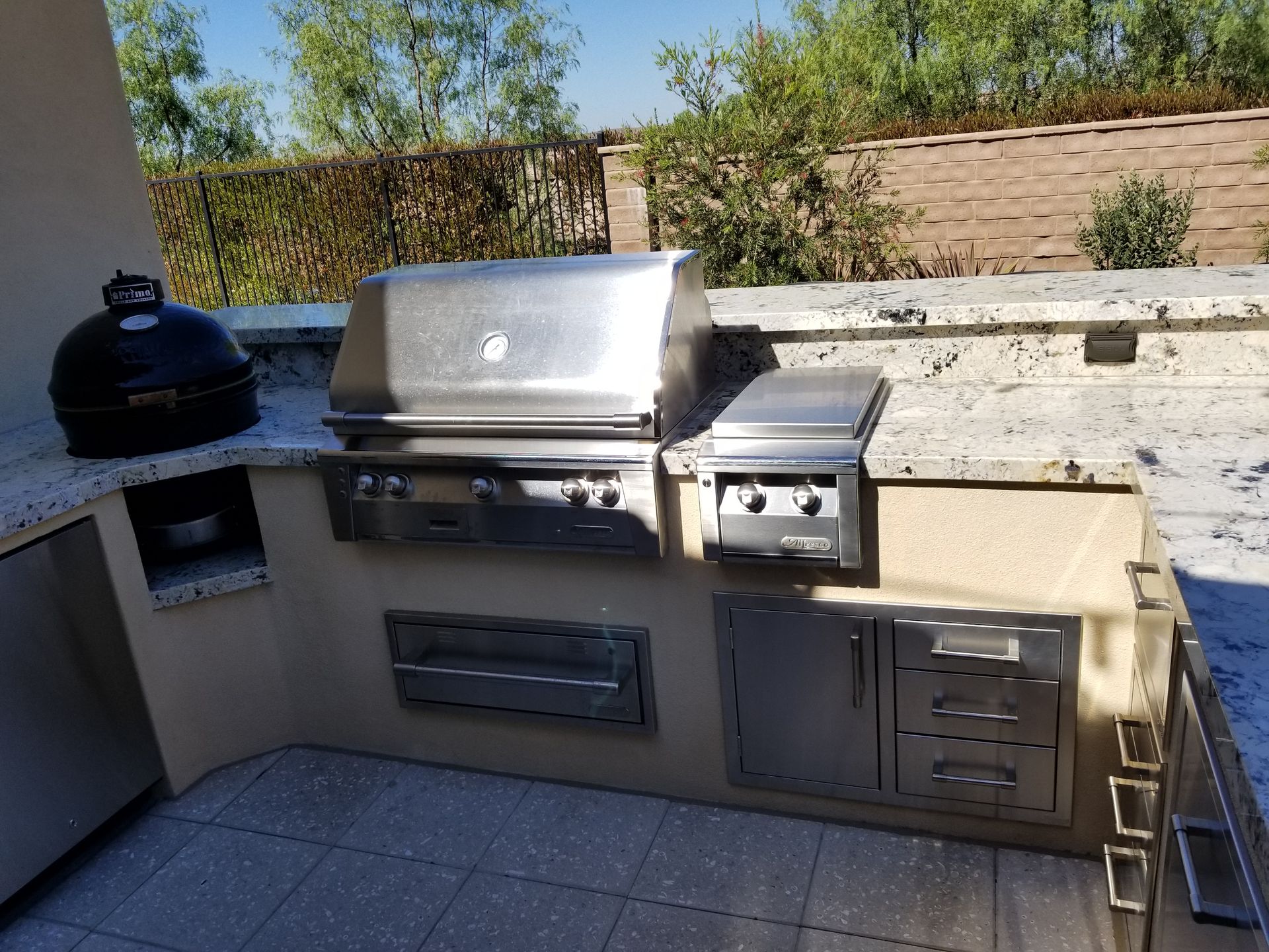 A stainless steel grill is sitting on top of a counter in an outdoor kitchen.