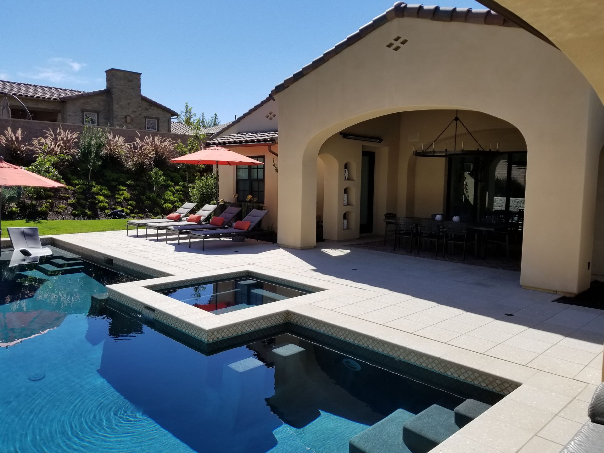 A large swimming pool is surrounded by chairs and umbrellas