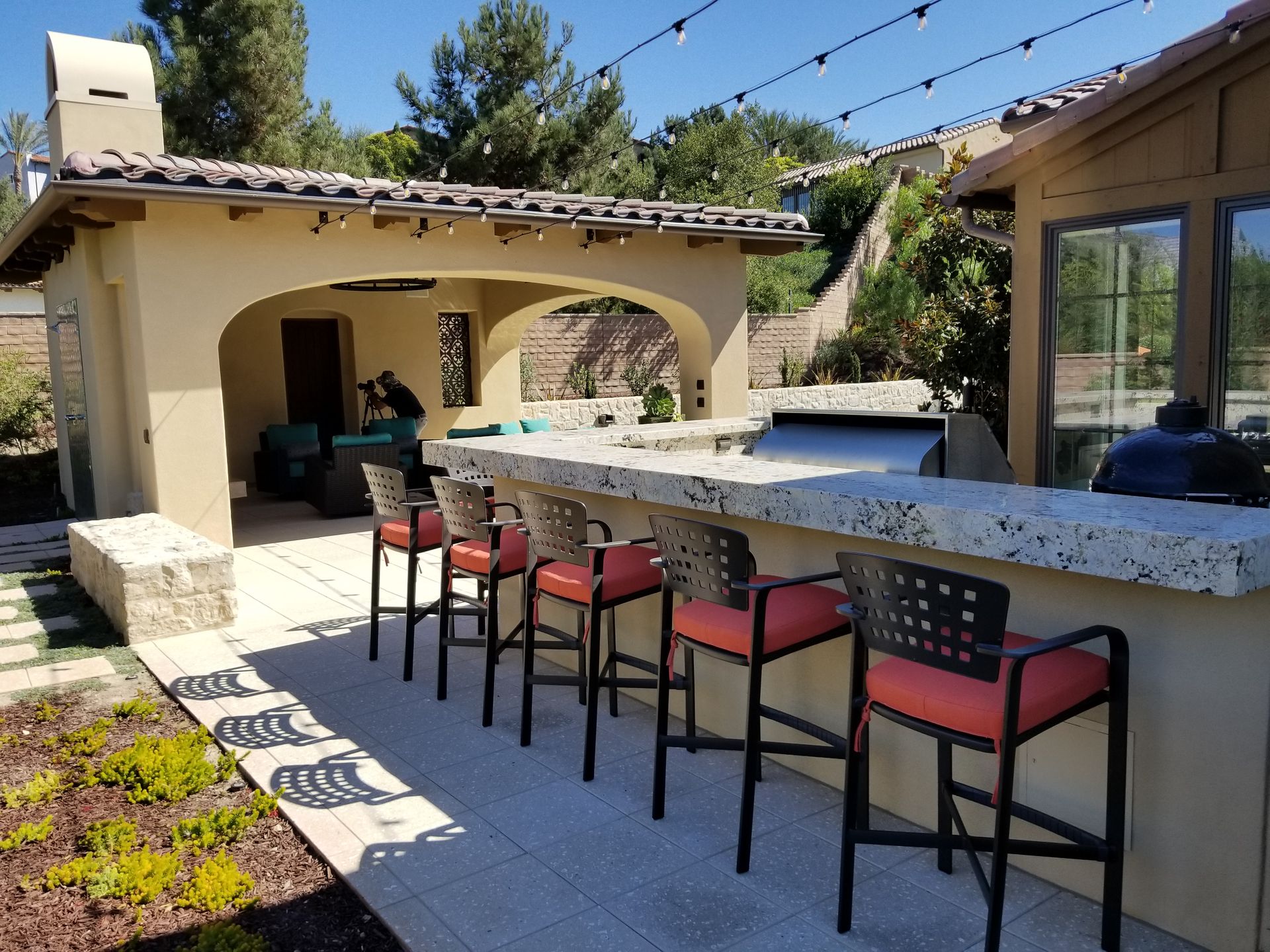 A patio with a bar and stools in front of a house