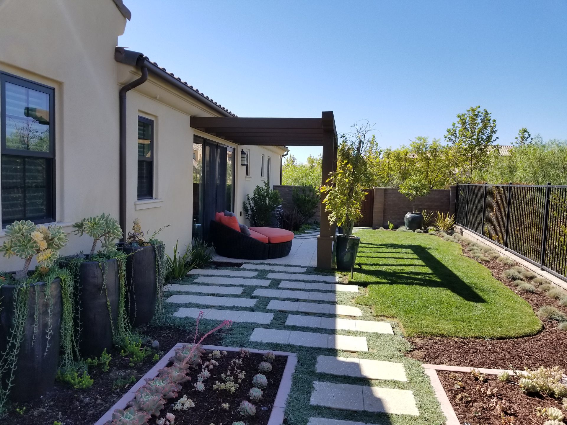 A house with a patio and a pergola in the backyard.