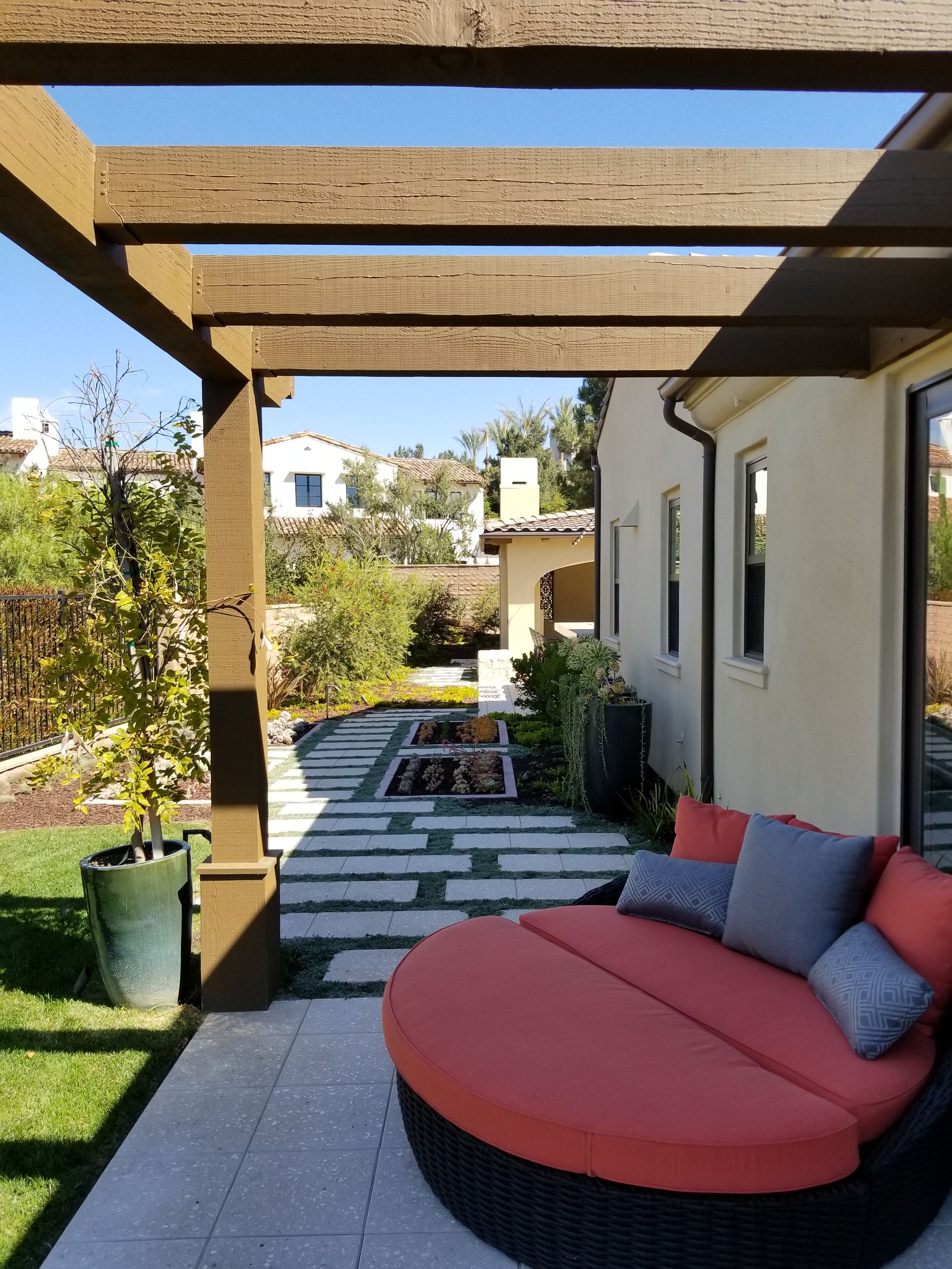 A patio with a couch and a fire pit under a pergola.