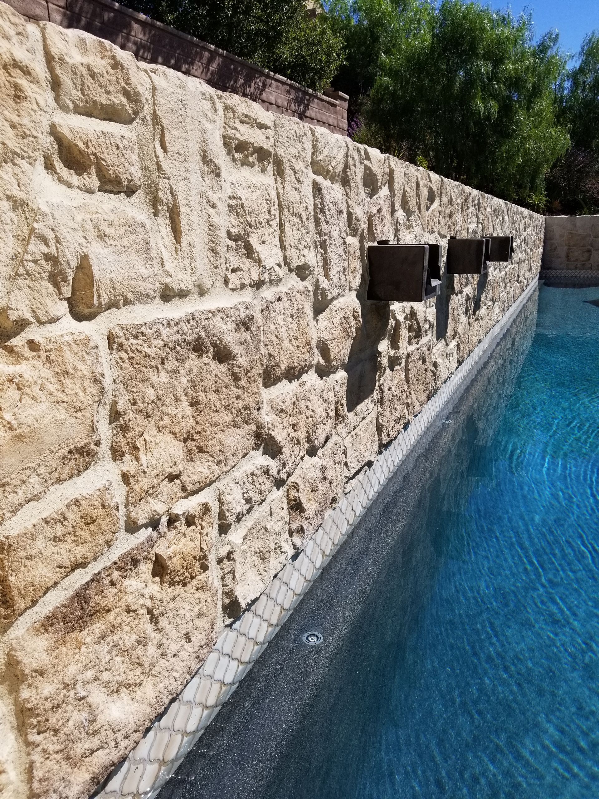A swimming pool with a stone wall surrounding it