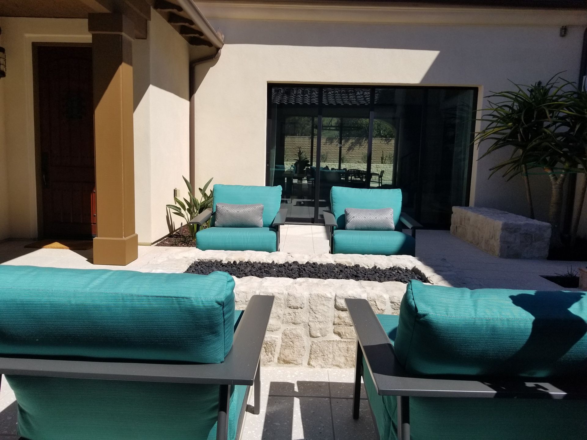 A patio with blue chairs and a couch in front of a house.