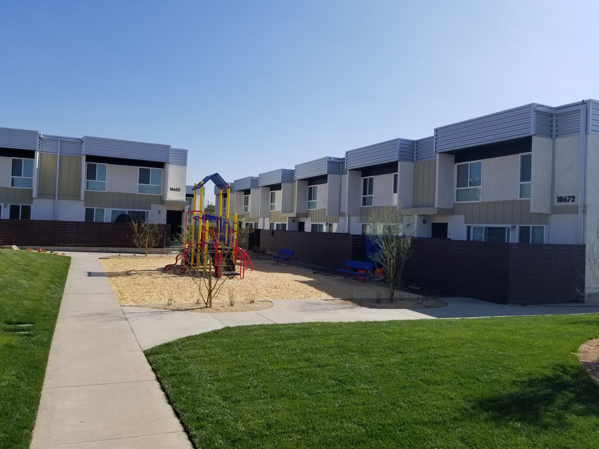 A playground in front of a row of apartment buildings.