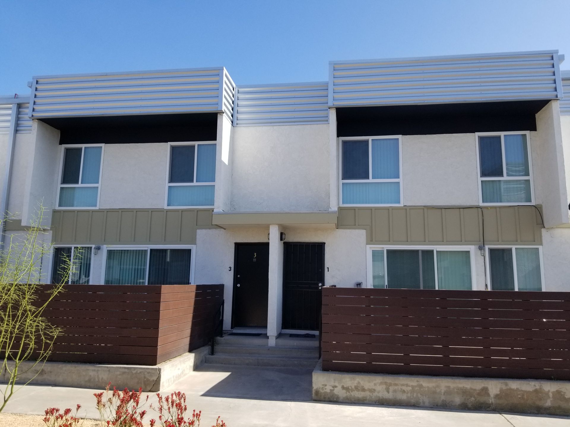 A white apartment building with a wooden fence in front of it