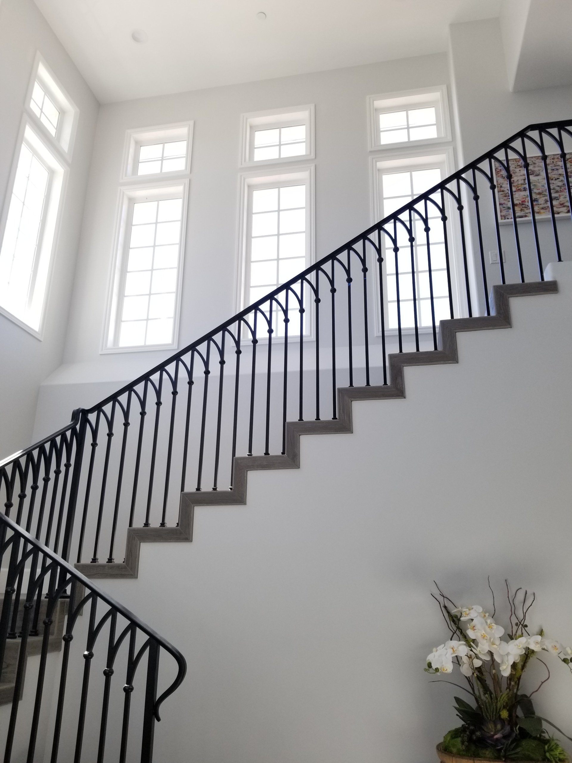 A staircase with a black railing in a white room