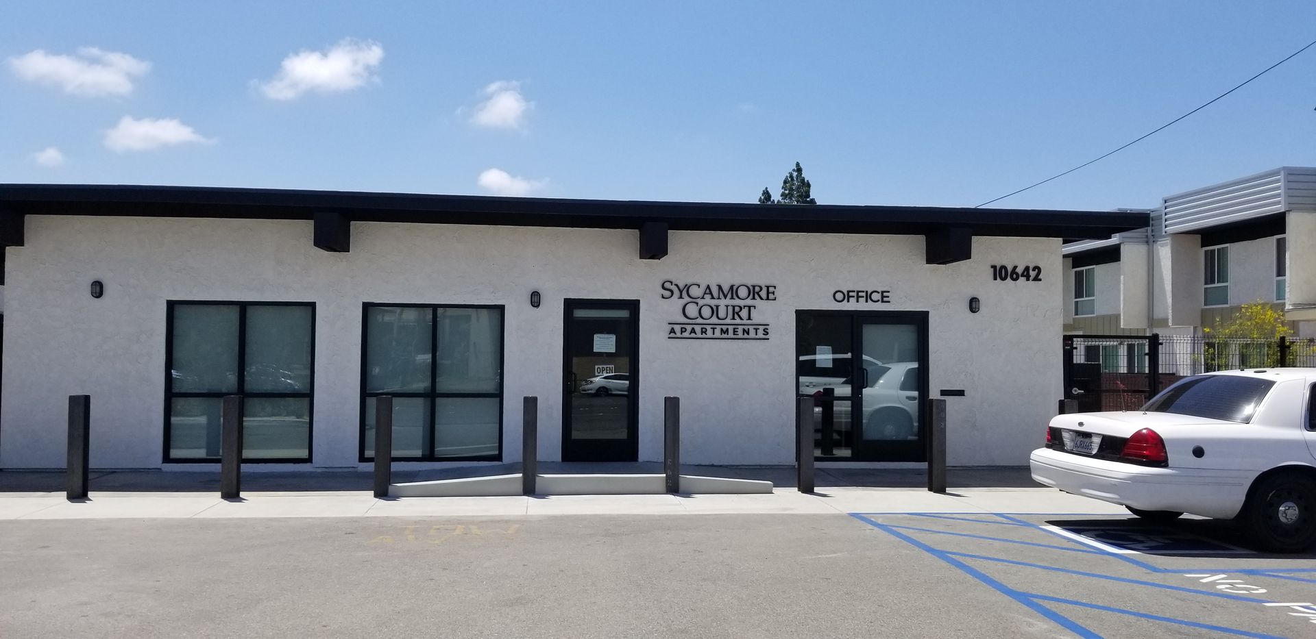 A white car is parked in front of a white building.