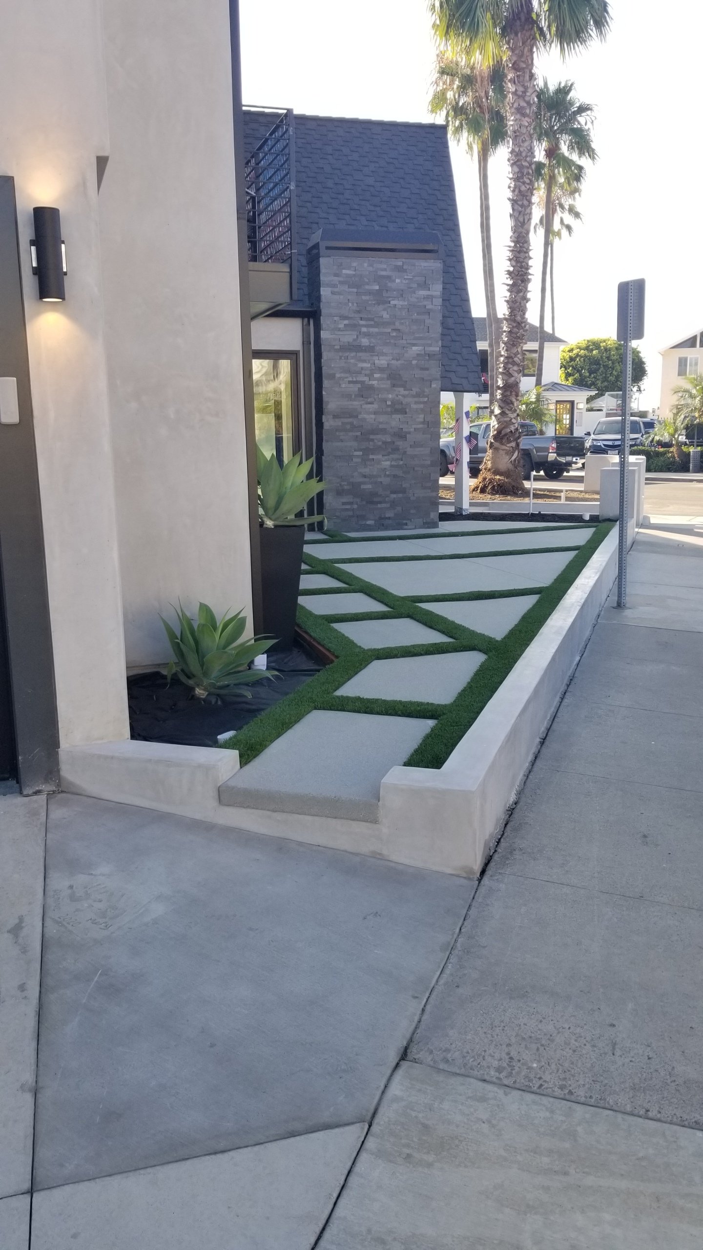 A concrete walkway leading to a house with palm trees in the background.