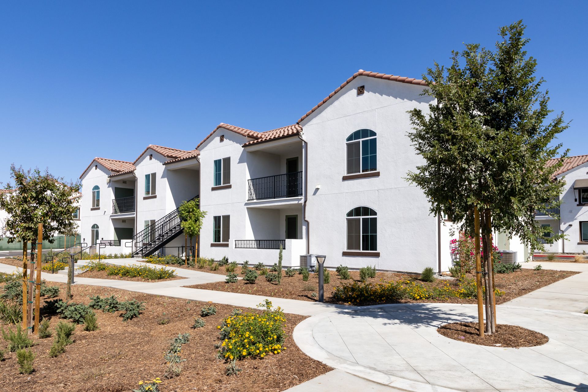 A large white apartment building with a walkway leading to it.
