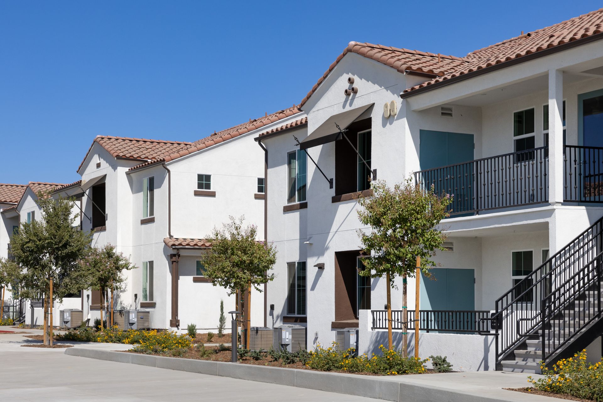 A row of white apartment buildings with balconies and stairs