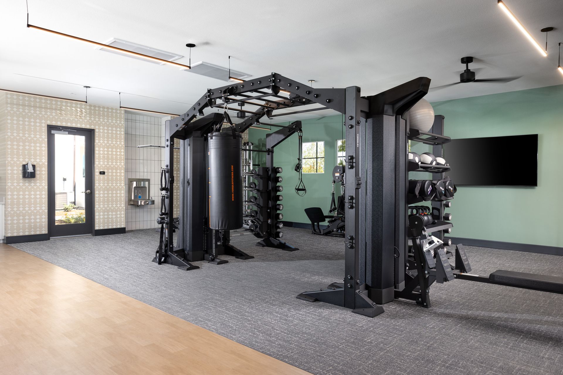 A large gym with a lot of equipment and a ceiling fan.