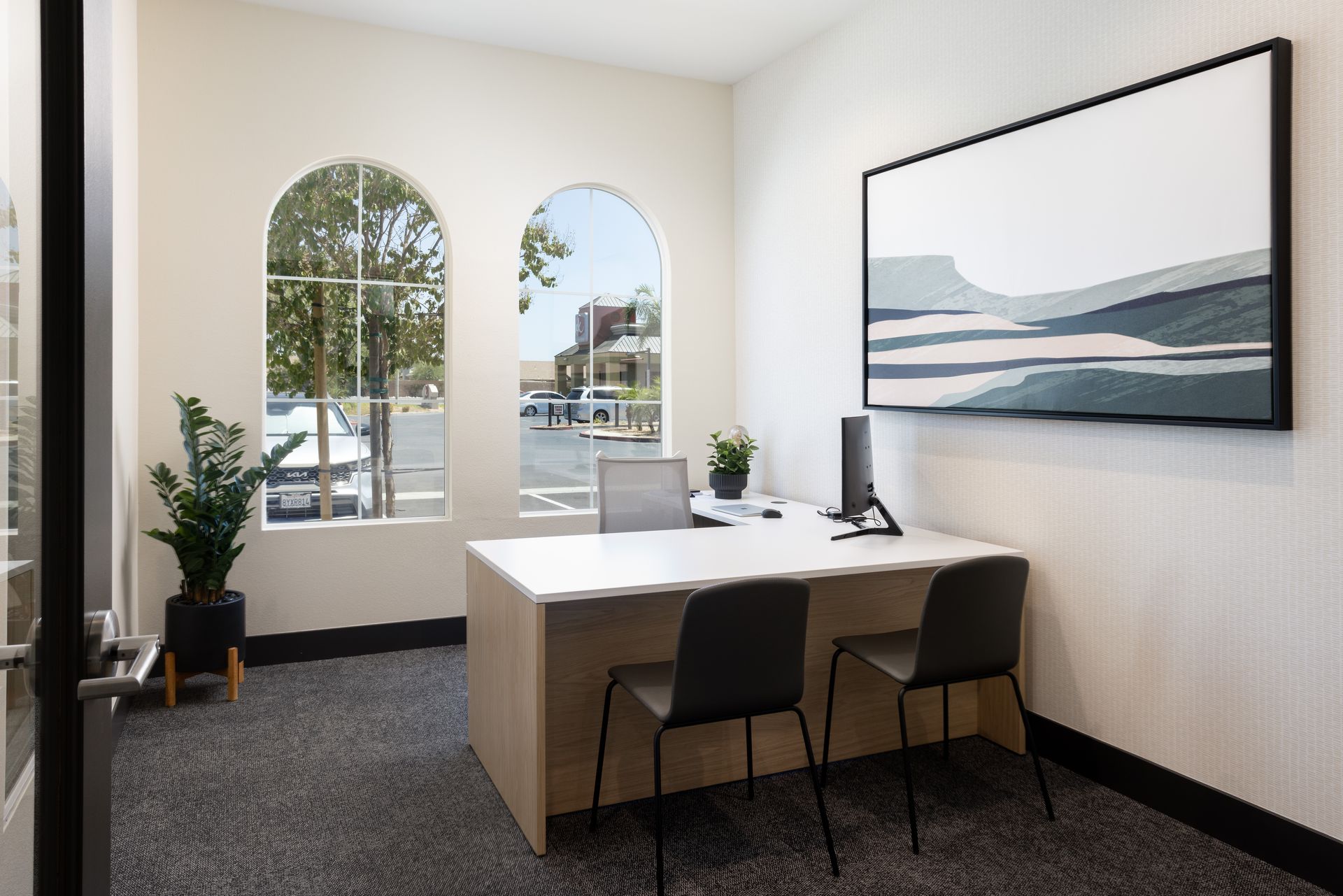 A small office with a desk and chairs and a large painting on the wall.
