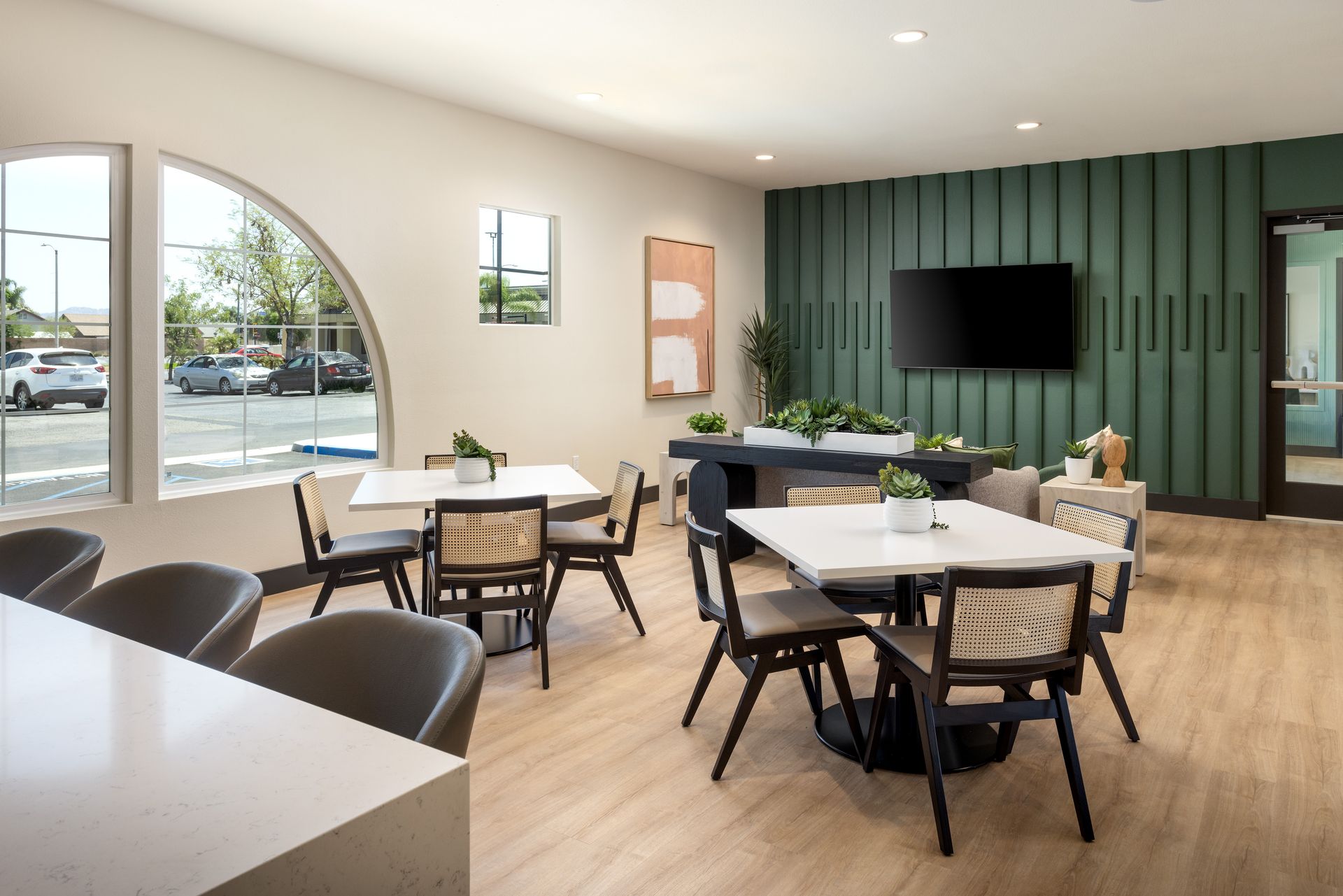 A kitchen with a stainless steel refrigerator , microwave , sink and bar stools.