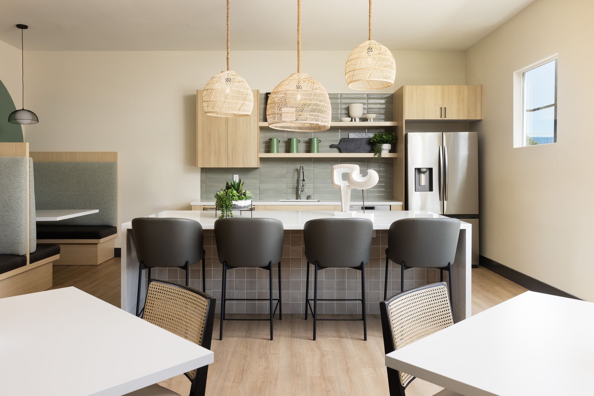 A kitchen with tables and chairs and a refrigerator.
