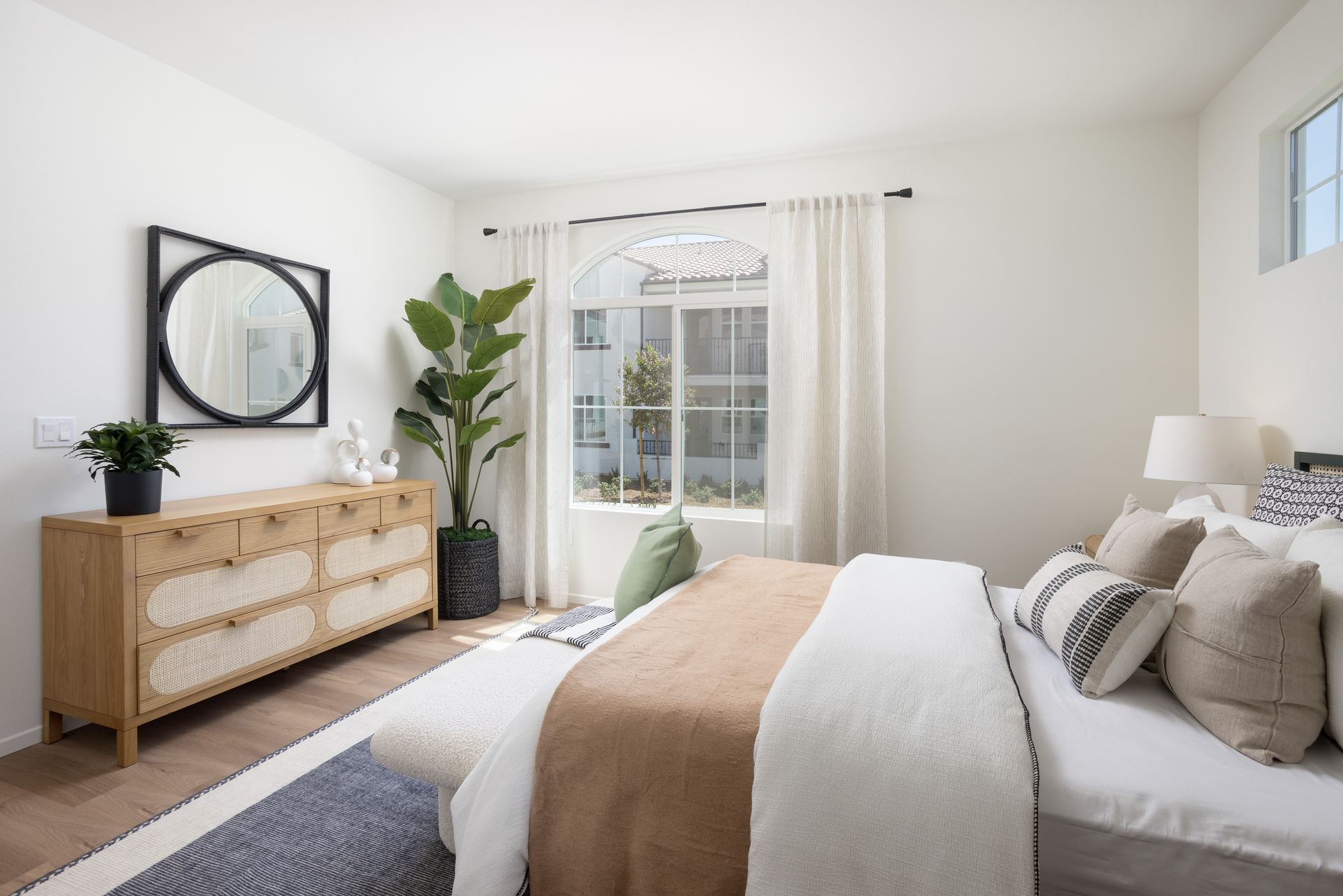 A bedroom with a bed , dresser , mirror and window.