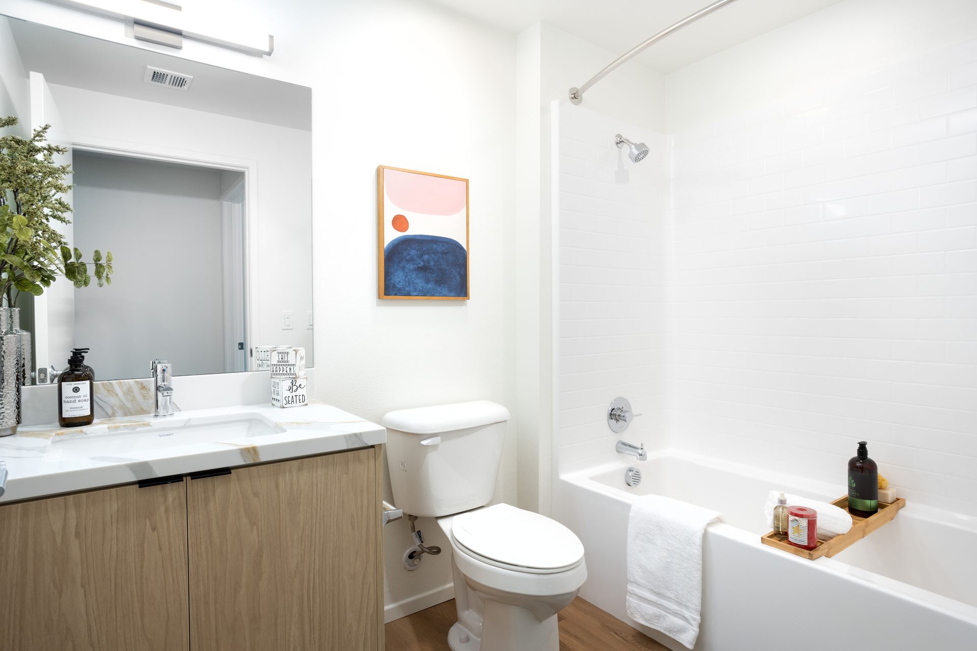 A bathroom with a toilet , sink , bathtub and mirror.