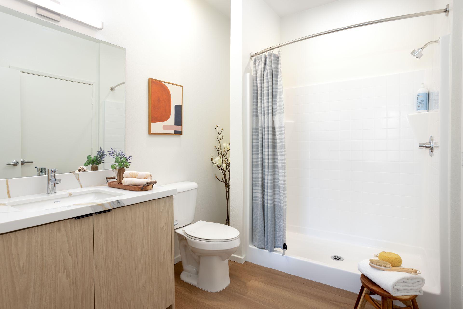 A bathroom with a toilet , sink , shower and mirror.