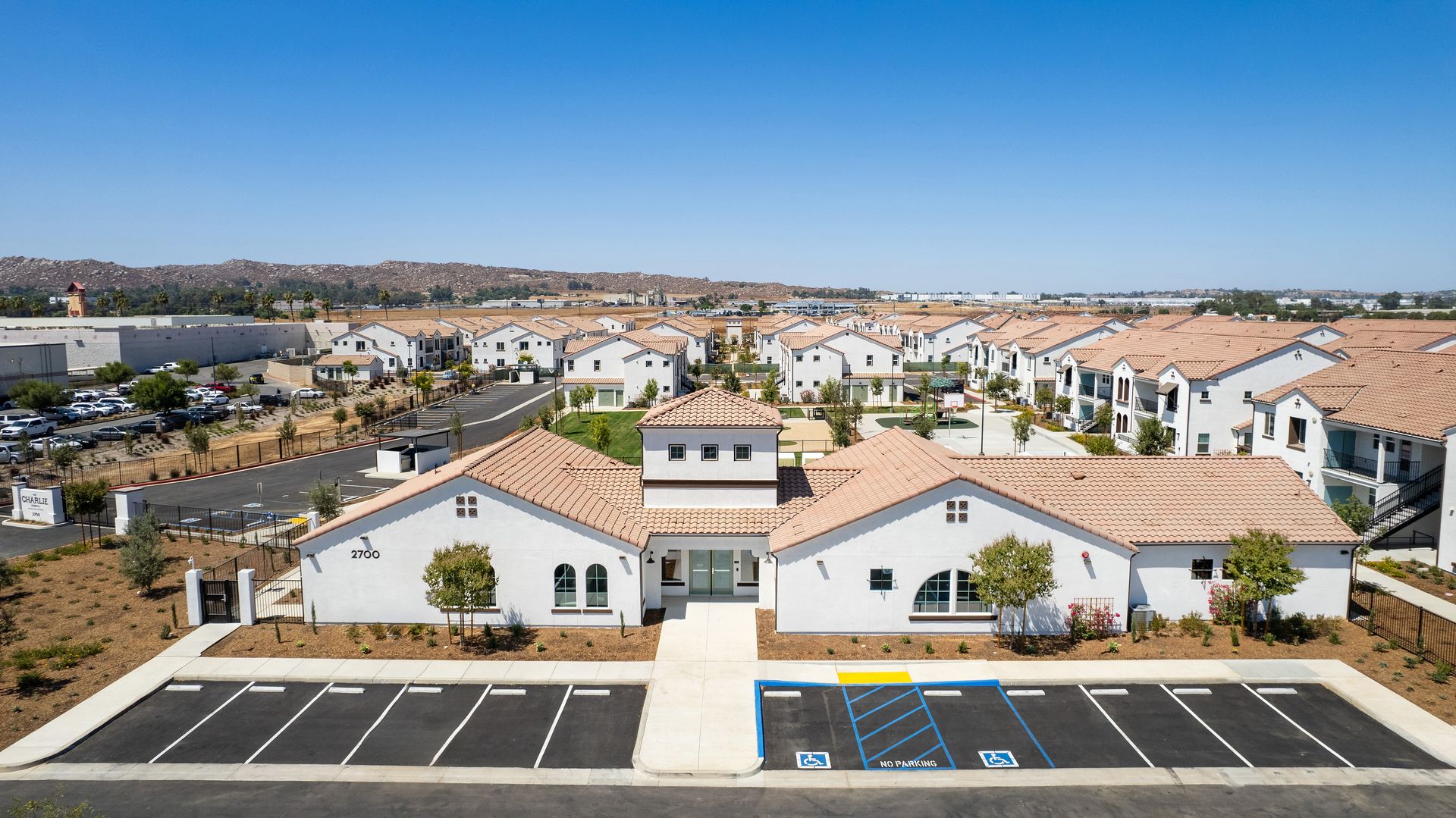 An aerial view of a large white building with a parking lot in front of it.