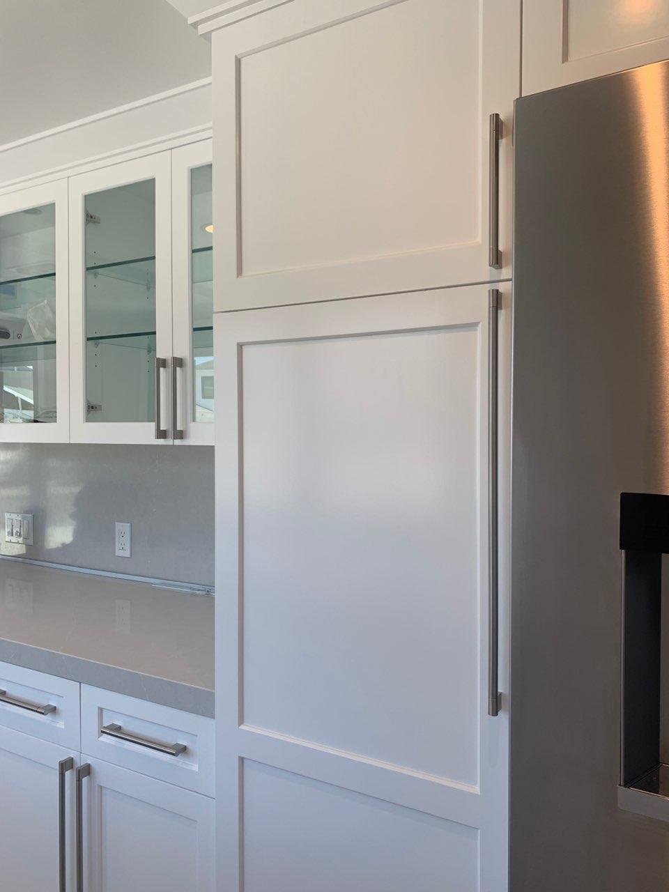 A kitchen with white cabinets and a stainless steel refrigerator