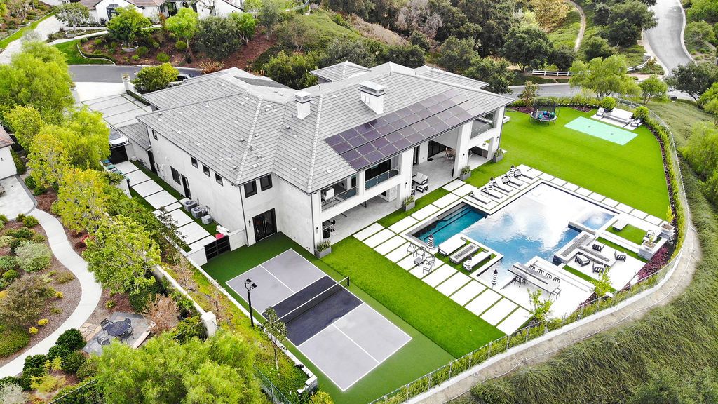 An aerial view of a large house with a swimming pool and tennis court.