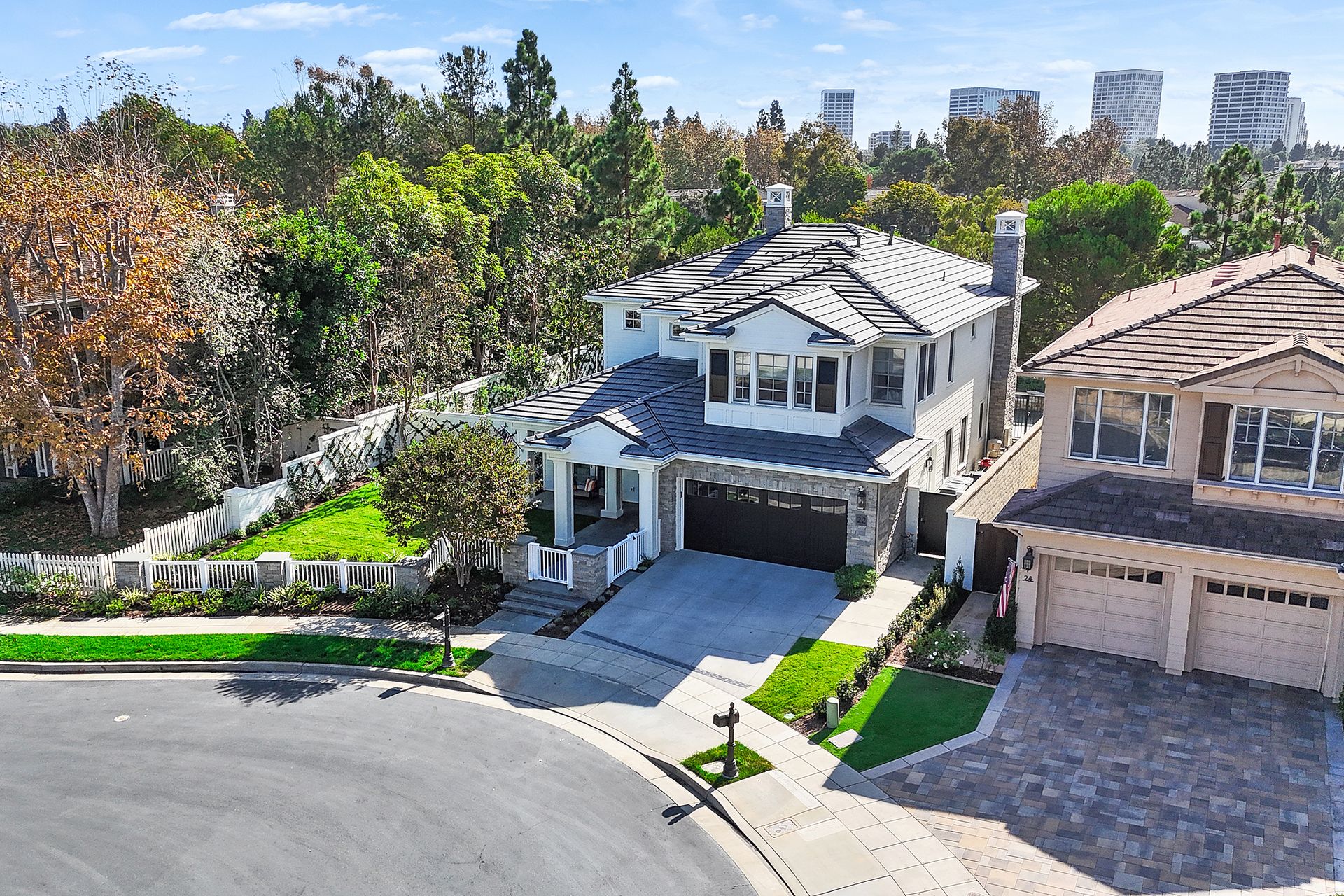 Two-story house with gray roof, white trim, and a driveway in a suburban neighborhood.