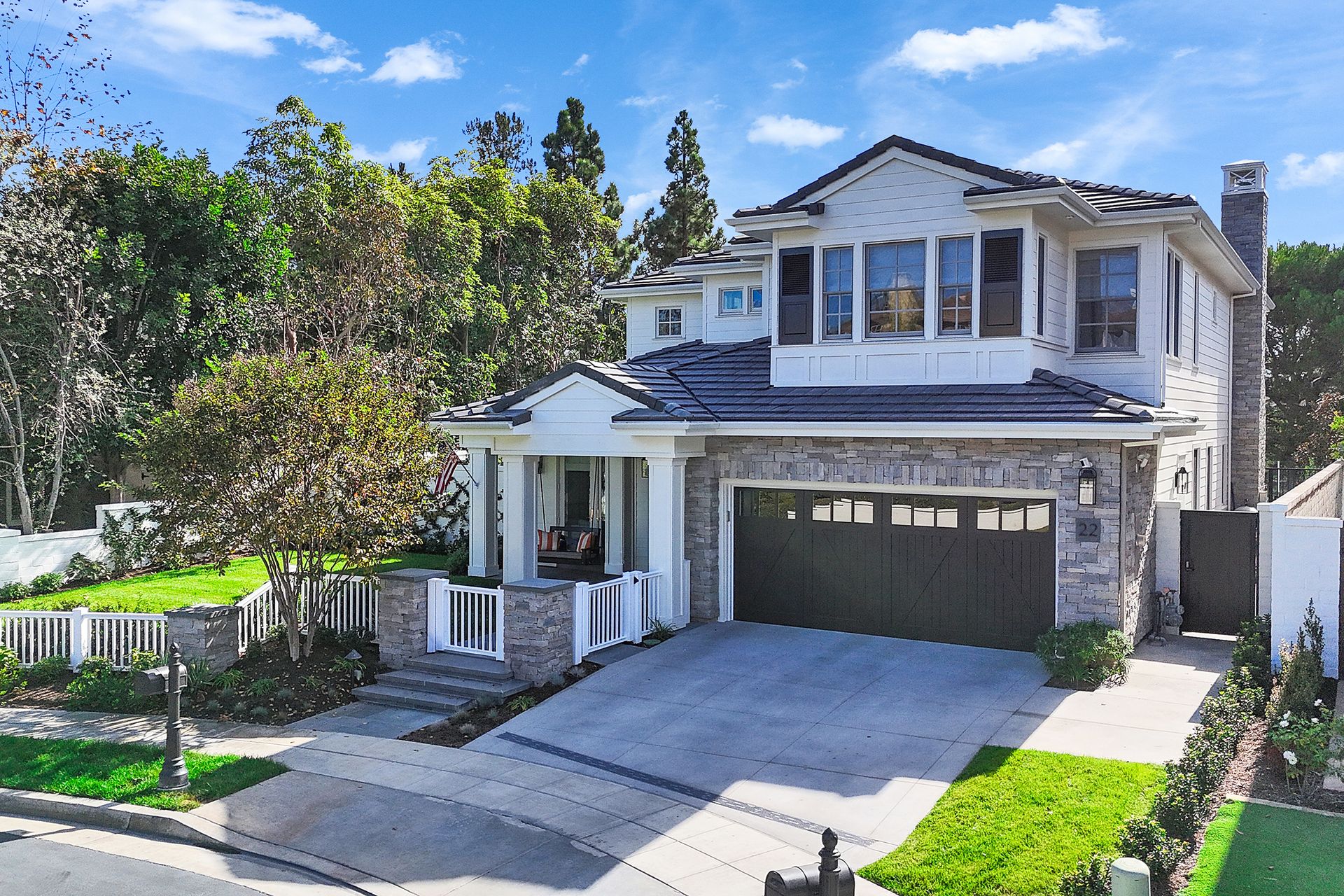 Two-story house with stone and white siding, driveway, and manicured lawn.