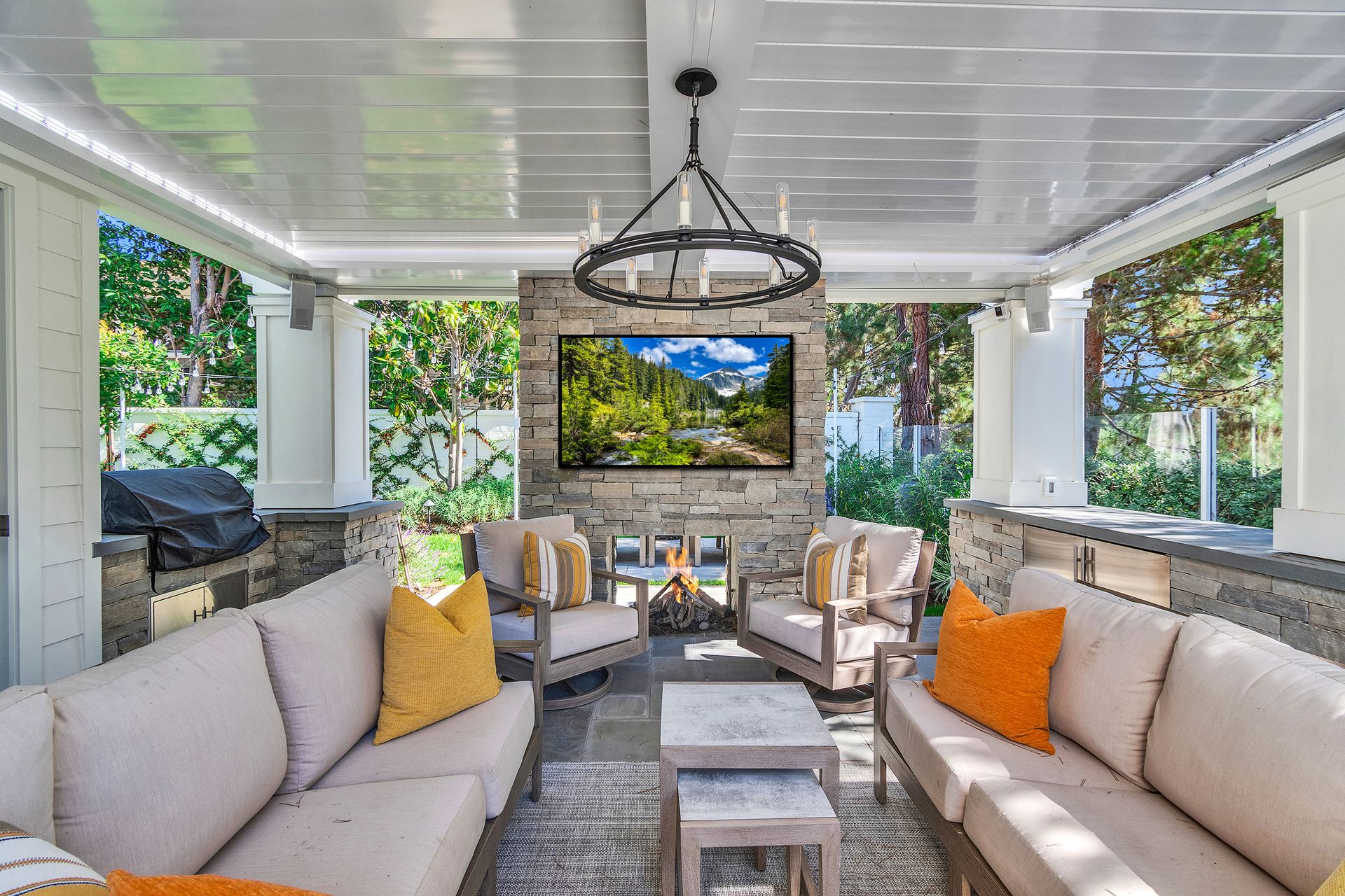 Outdoor living space with sectional sofa, fireplace, TV, and chandelier.