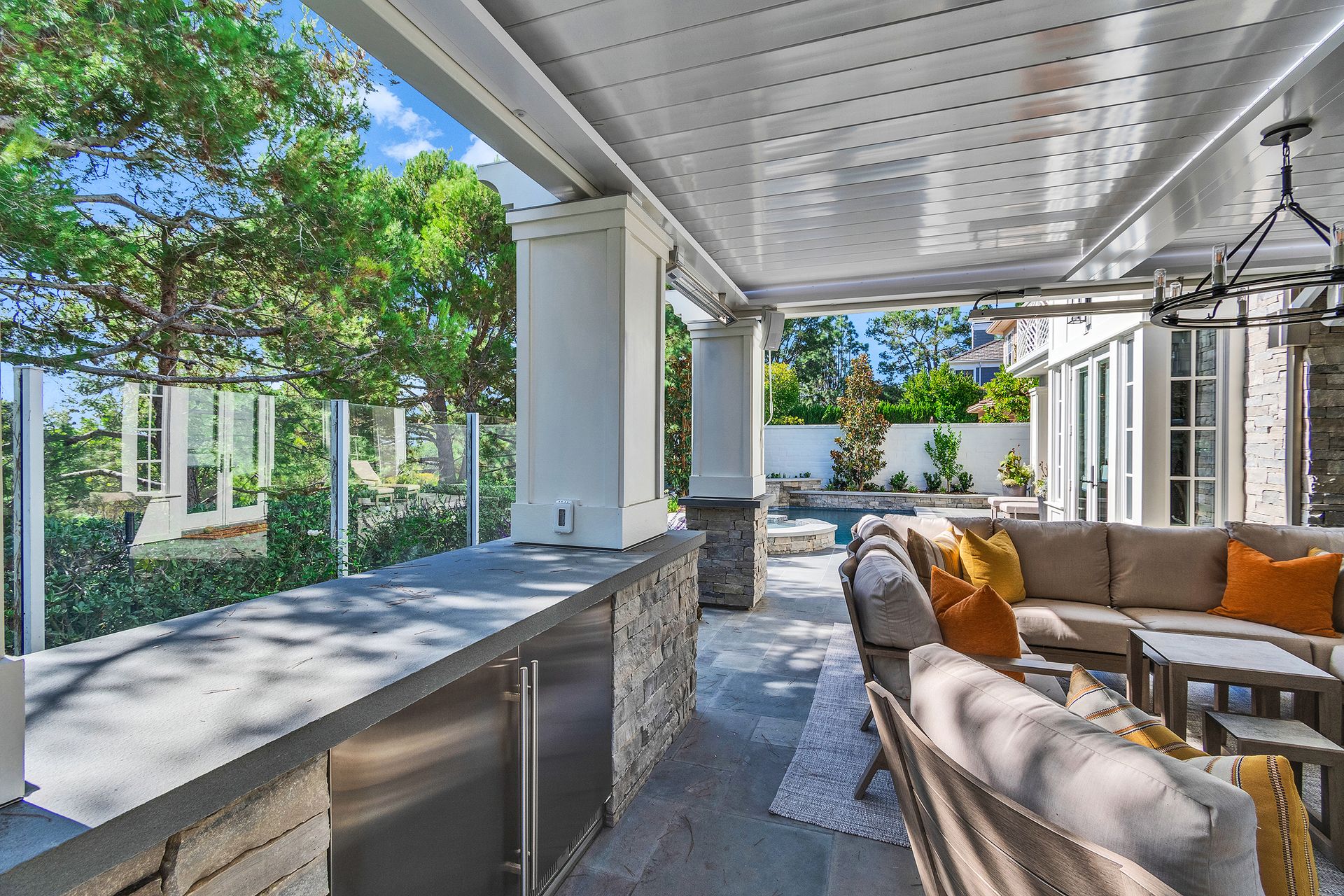 Covered outdoor patio with a stone bar, seating, and a view of the yard.
